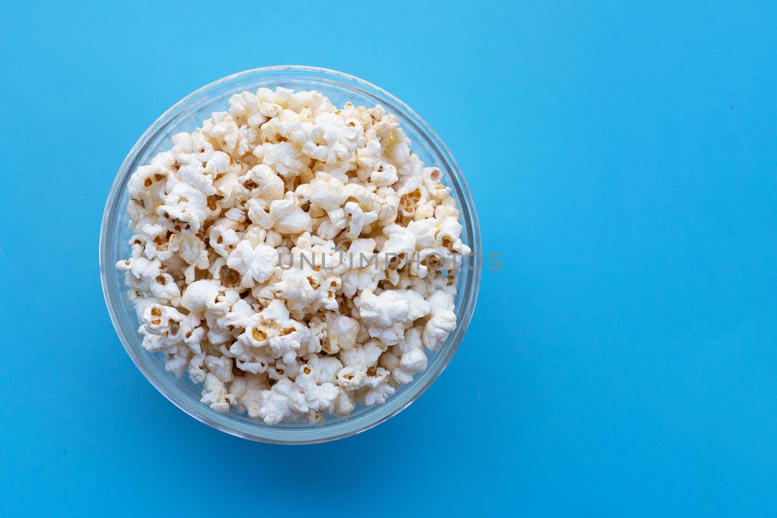 Popcorn on blue background. Copy space by Bowonpat