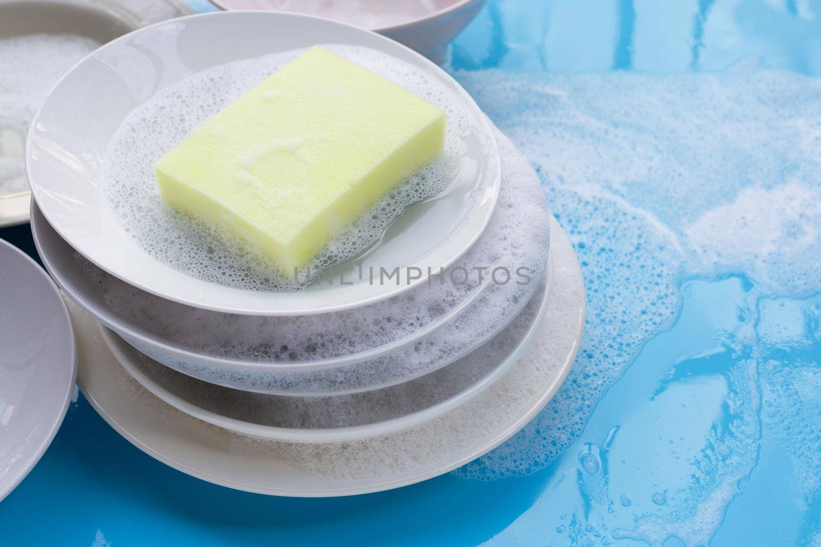 Washing dishes concept. wet blue with soapy foam background. by Bowonpat