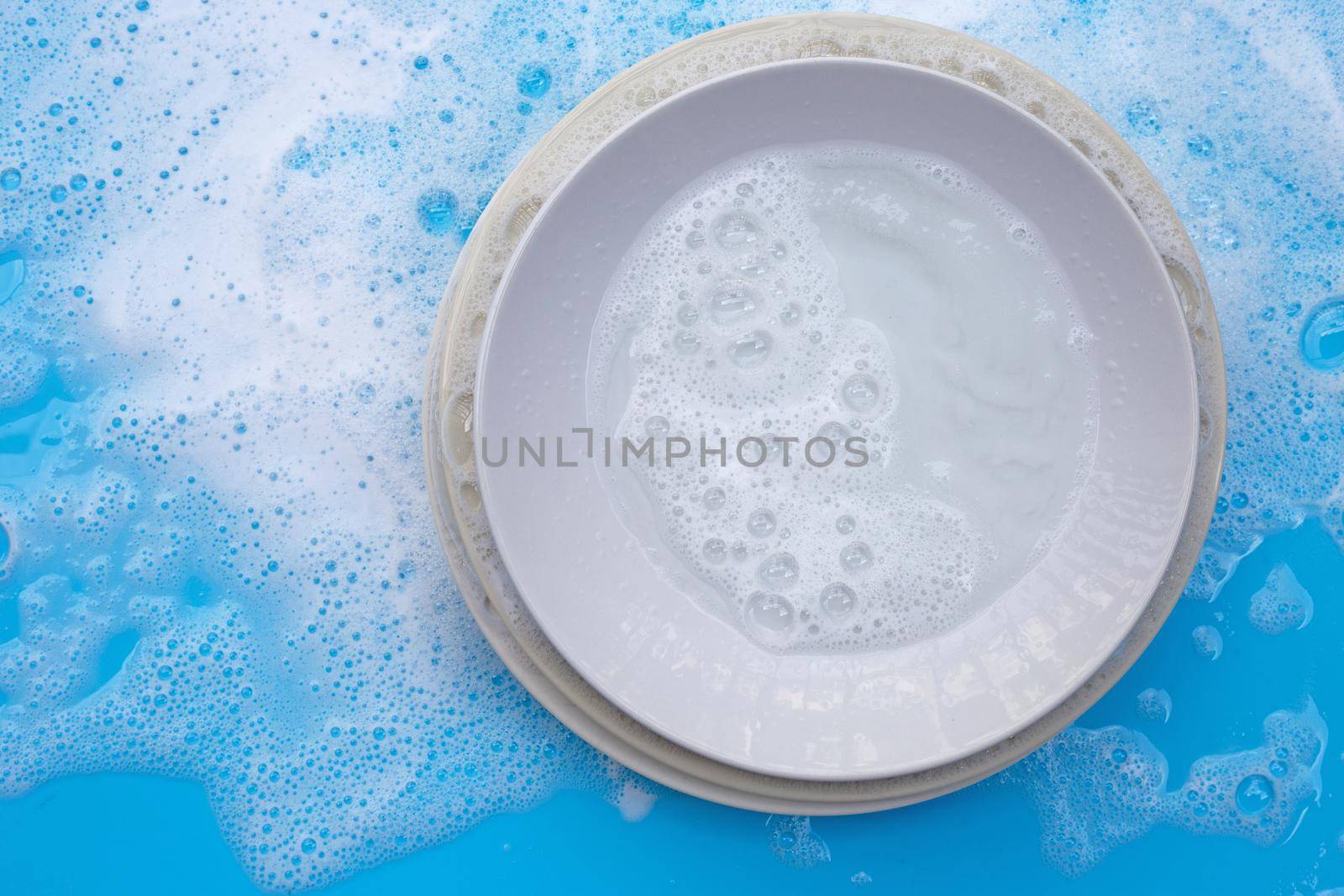Washing dishes concept. wet blue with soapy foam background. by Bowonpat