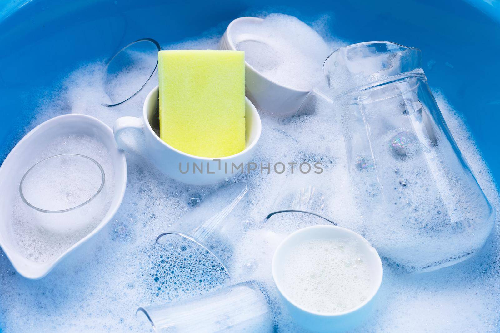 Washing used drinking glasses and cups with yellow sponge by Bowonpat