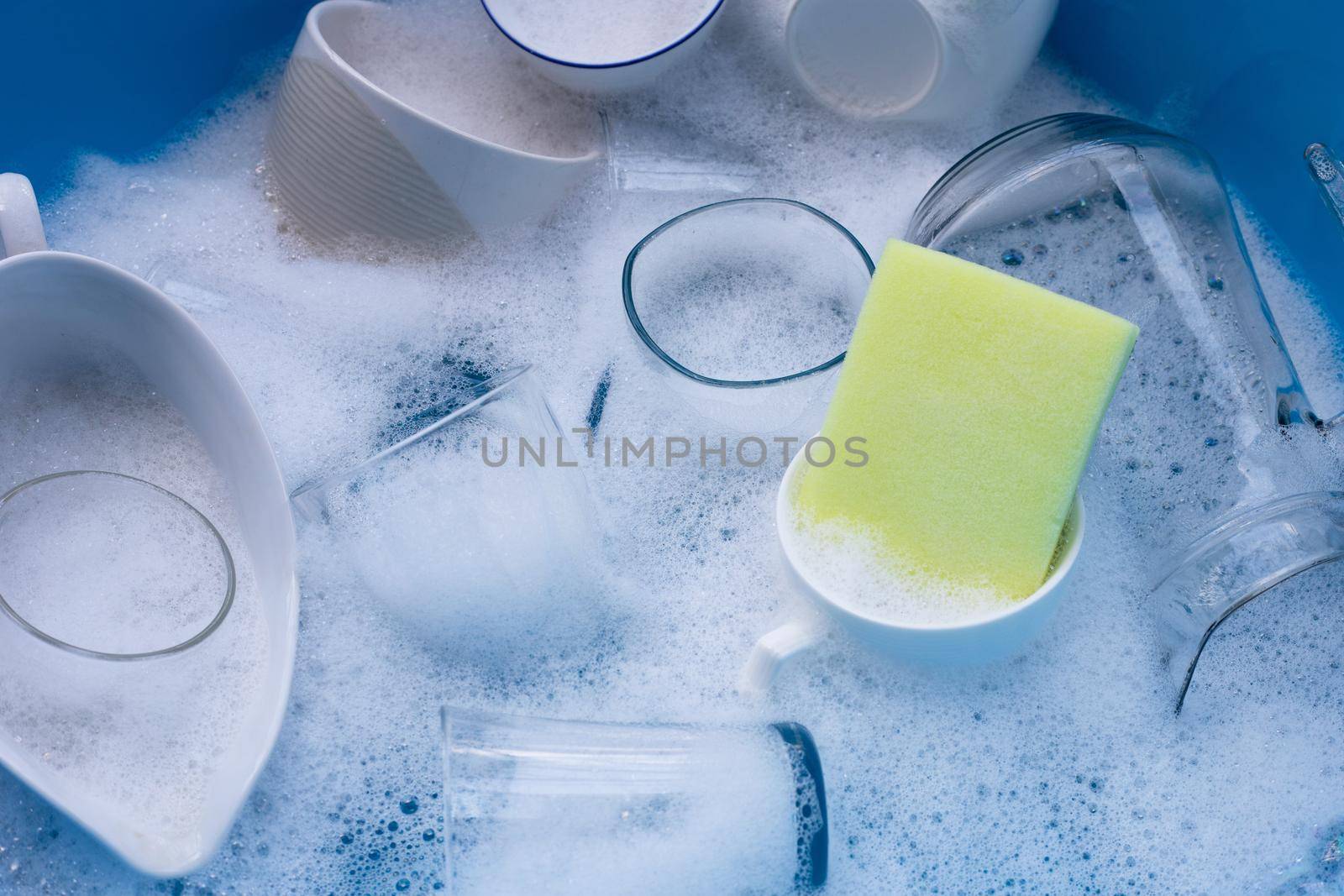 Washing used drinking glasses and cups with yellow sponge