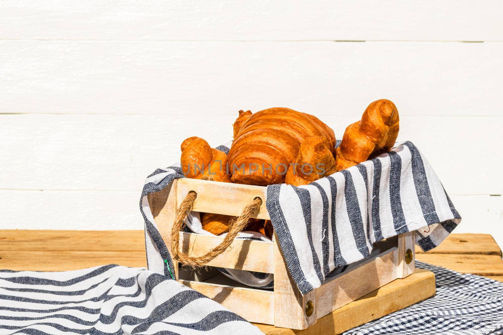 Fresh croissant, puff pastry and buttered french croissant on wooden crate. Food and breakfast concept. Detail of desserts and fresh pastries