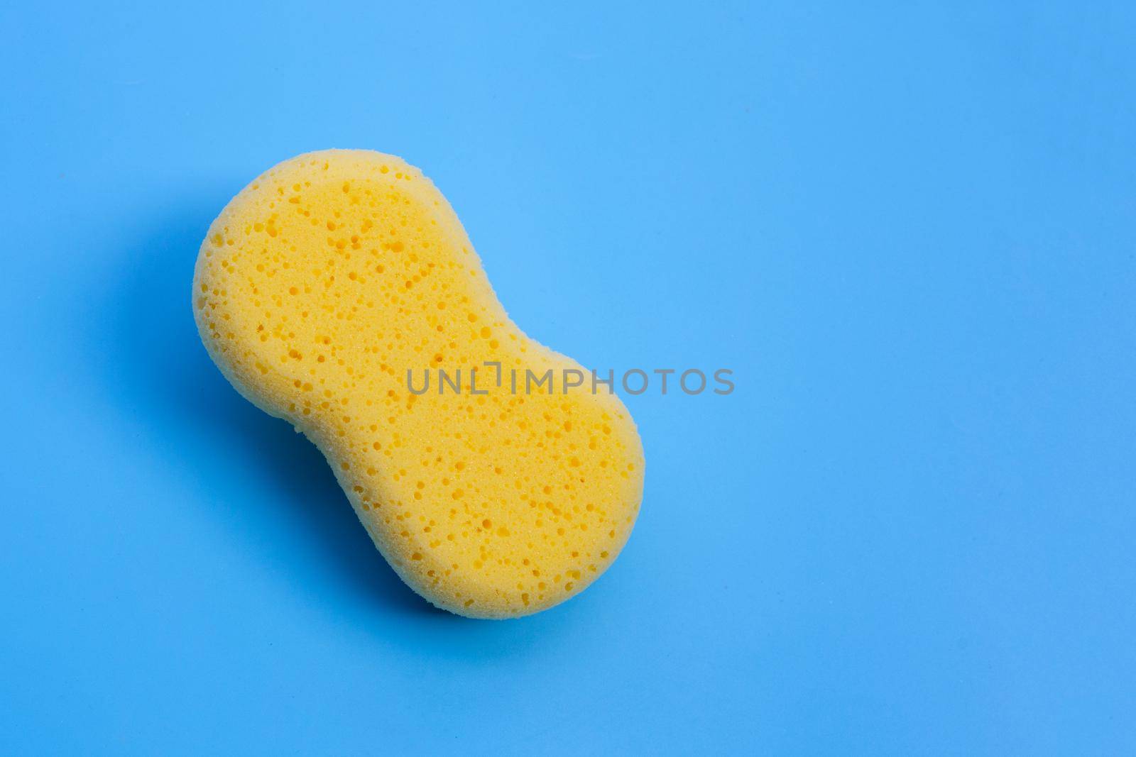 Yellow sponge on blue background.  Copy space