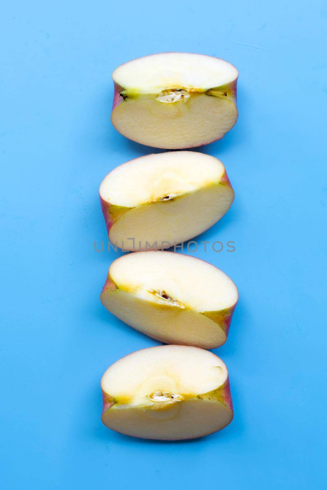 Ripe apple slices on blue background. by Bowonpat