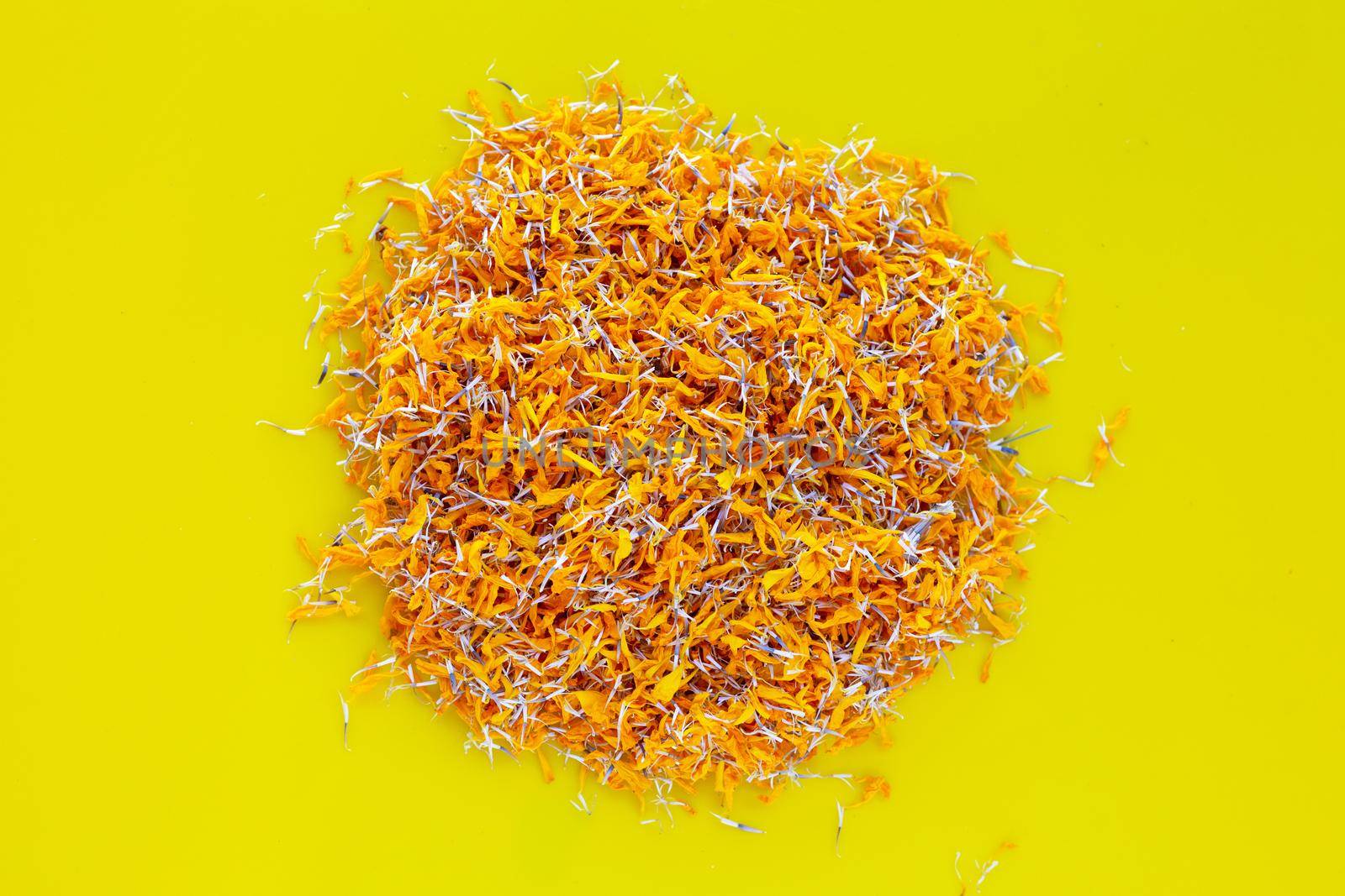 Petals of marigold flower on yellow background.