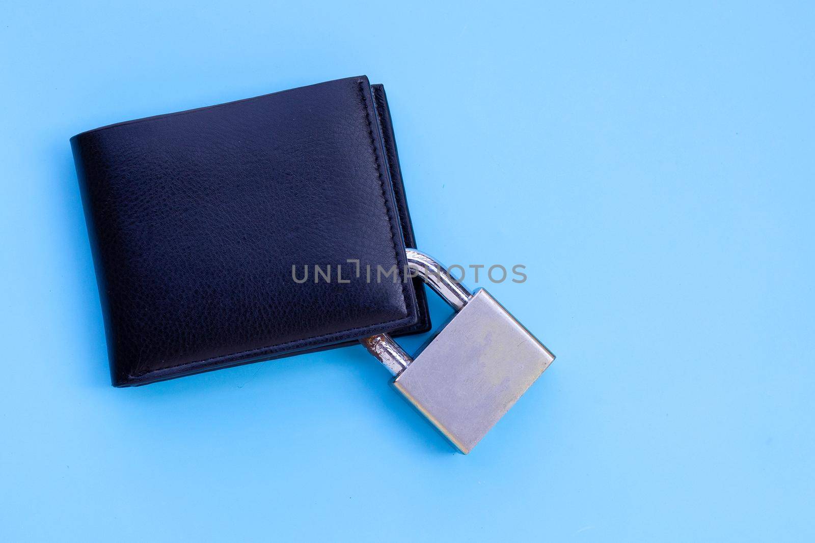 Wallet with padlock on blue background. Copy space