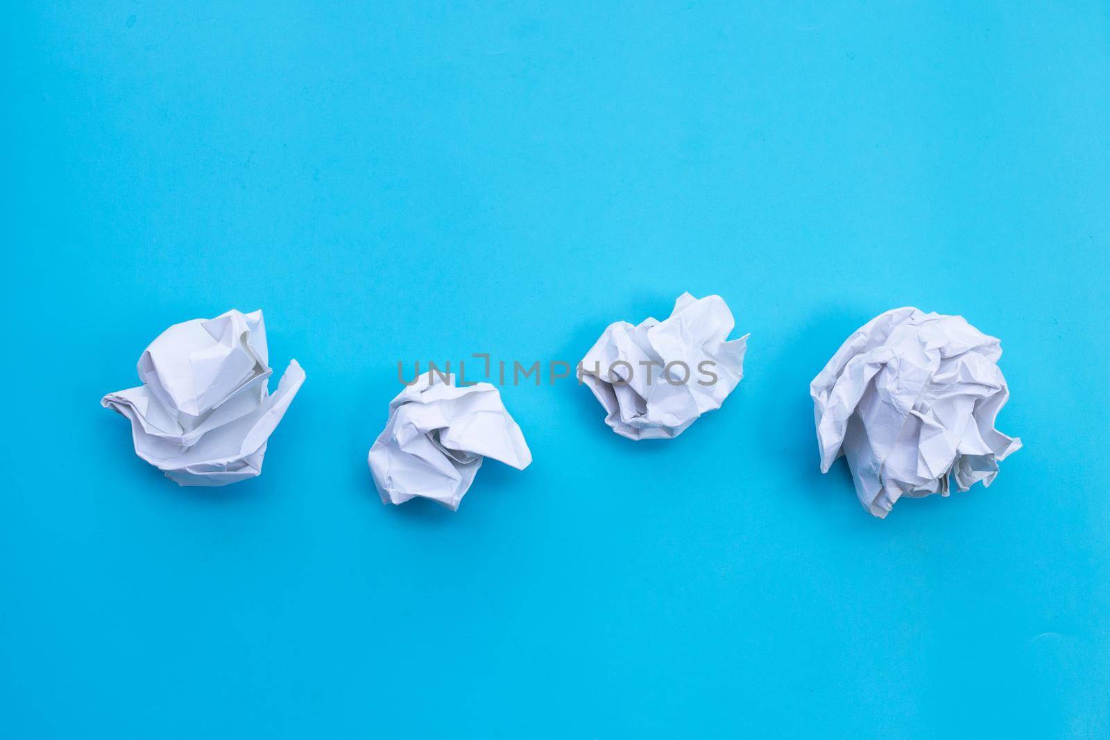 White crumpled paper on blue background. Ideas and creative thinking concept. Top view