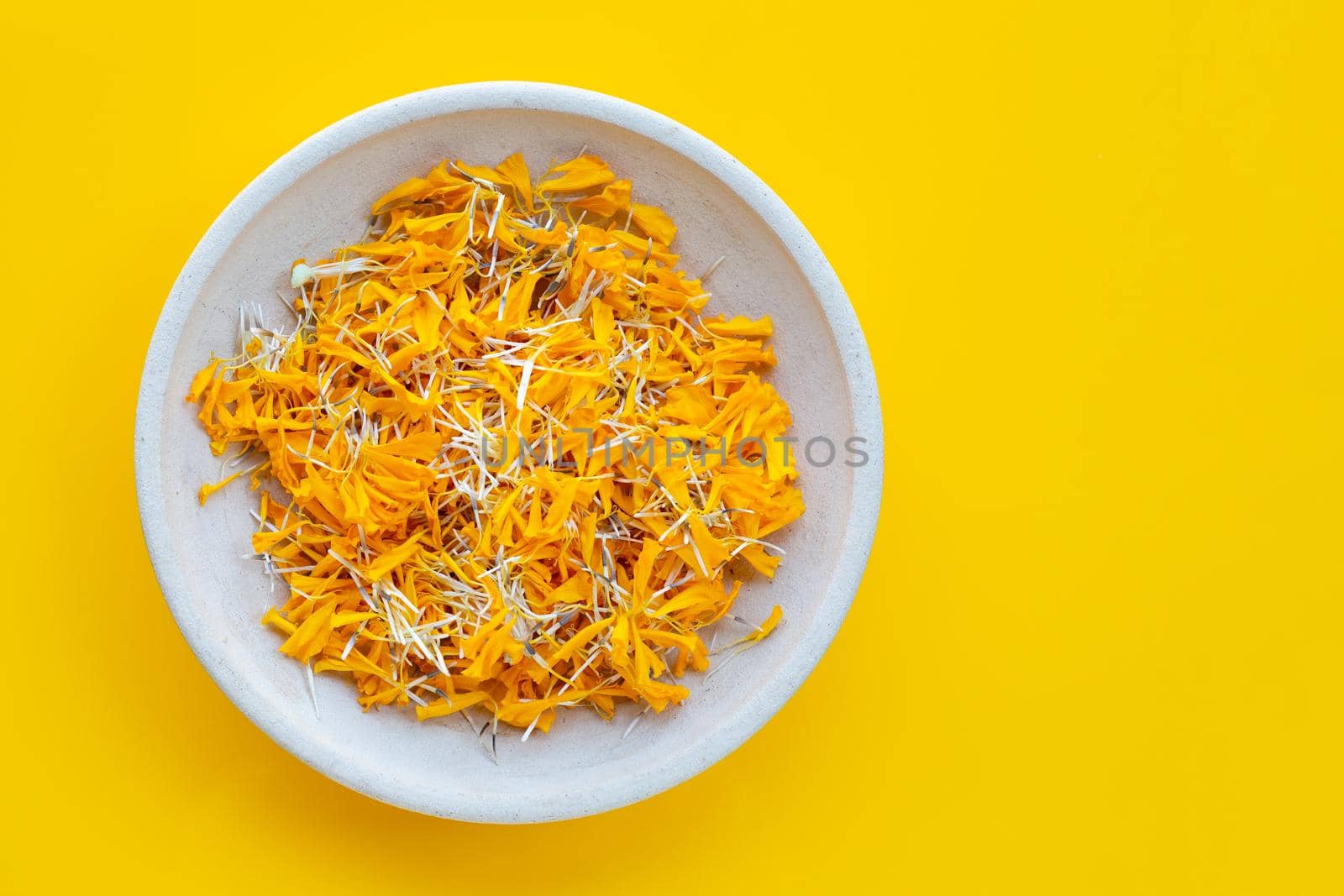 Petals of marigold flower on yellow background.