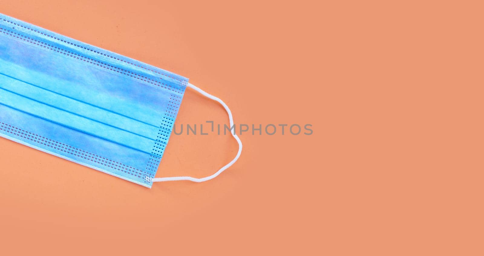 Protective medical mask on orange background. Top view