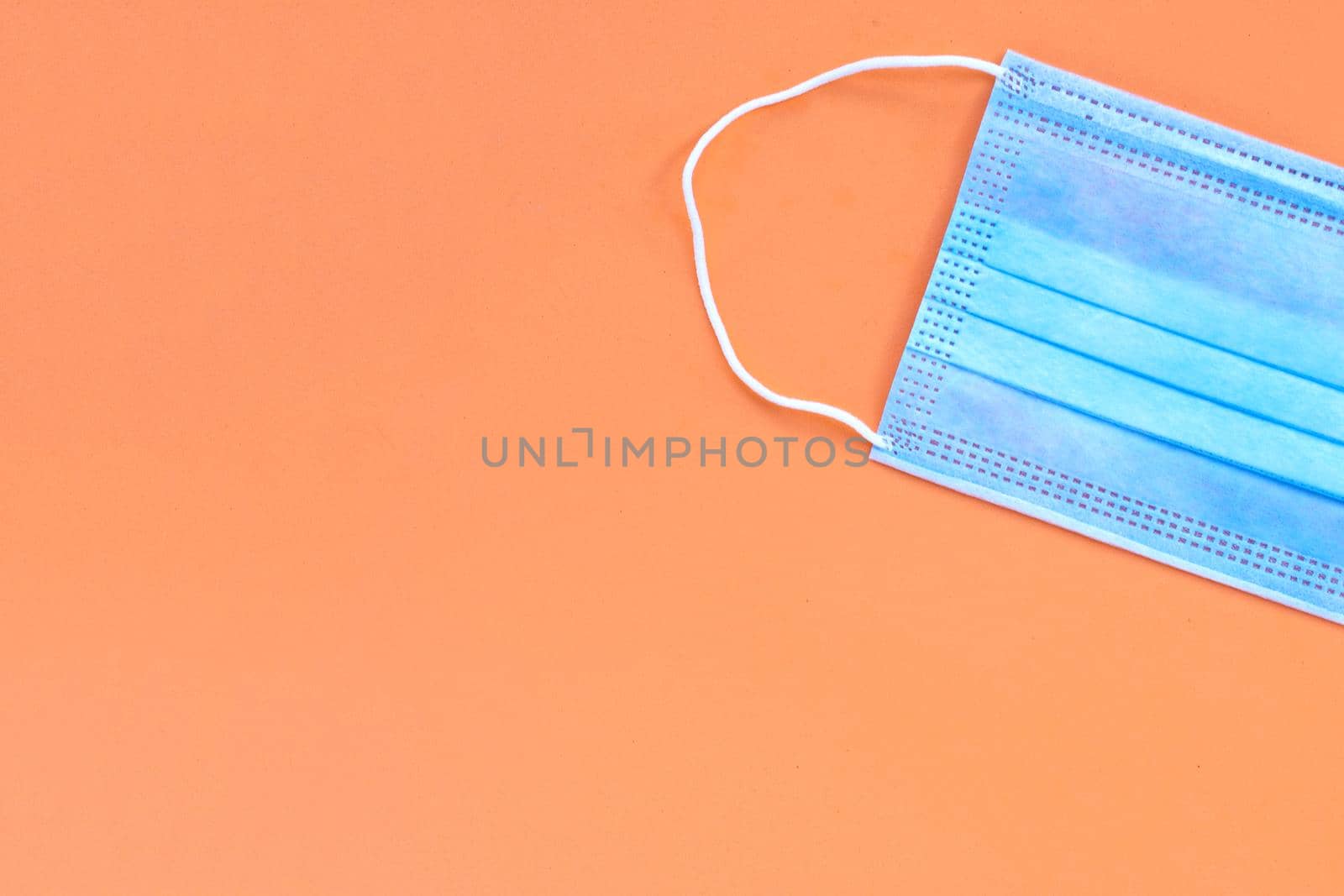 Protective medical mask on orange background. Top view