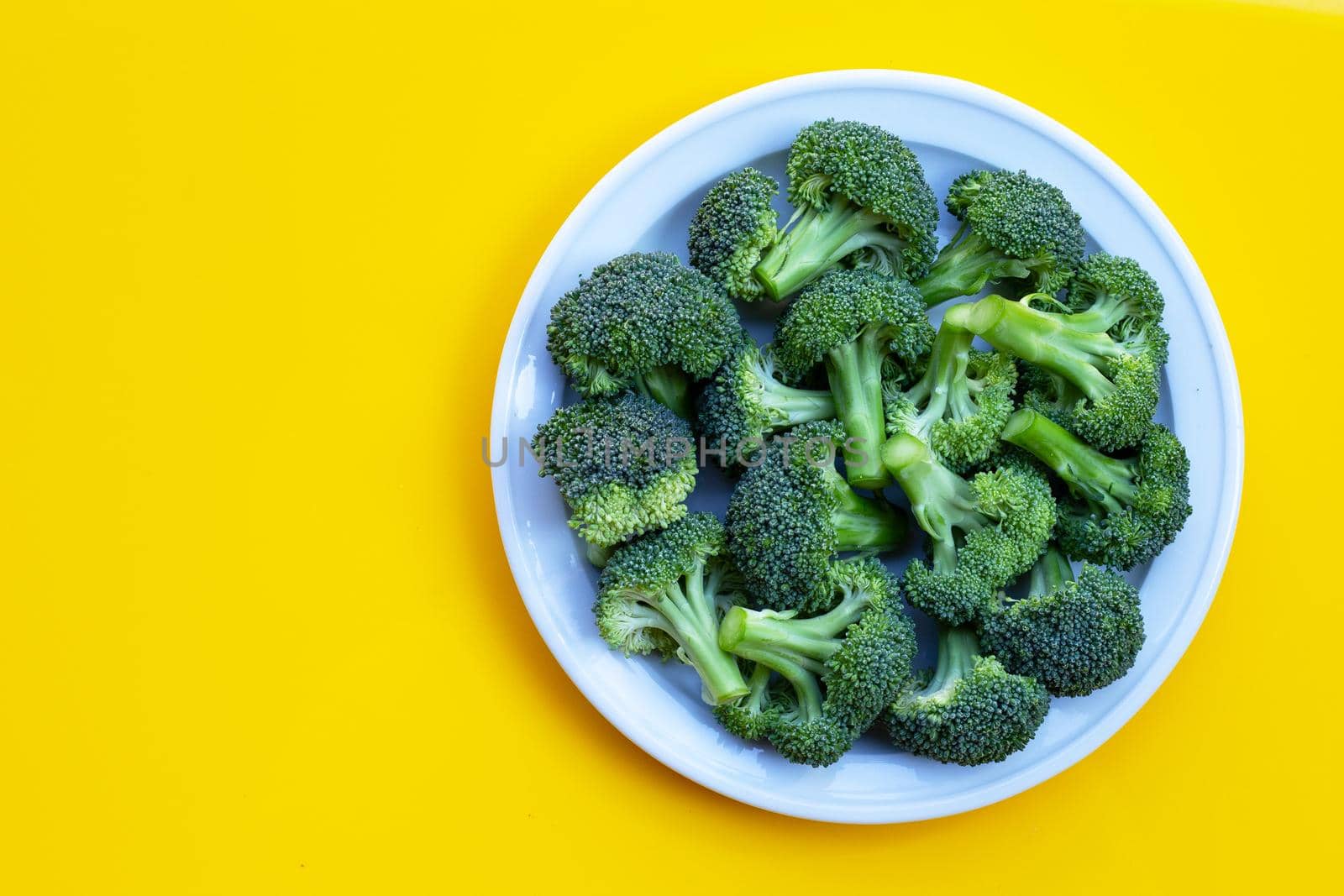 Fresh green broccoli on yellow background.