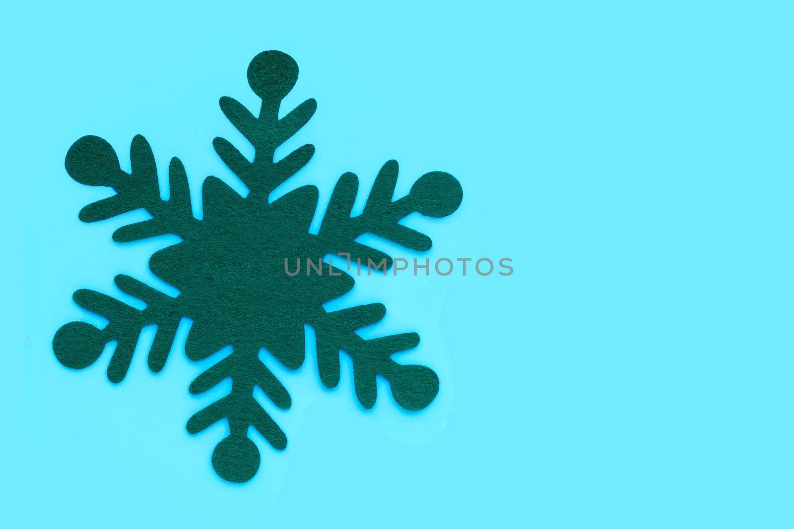 Green christmas snowflake on blue background.