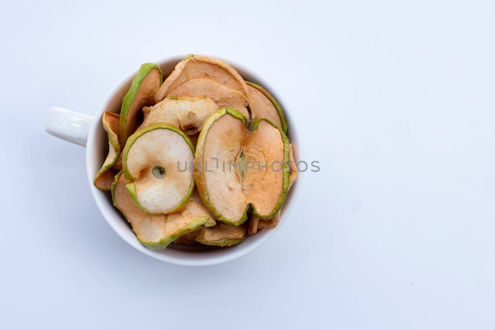 Dried apple slices in white cup on white background
