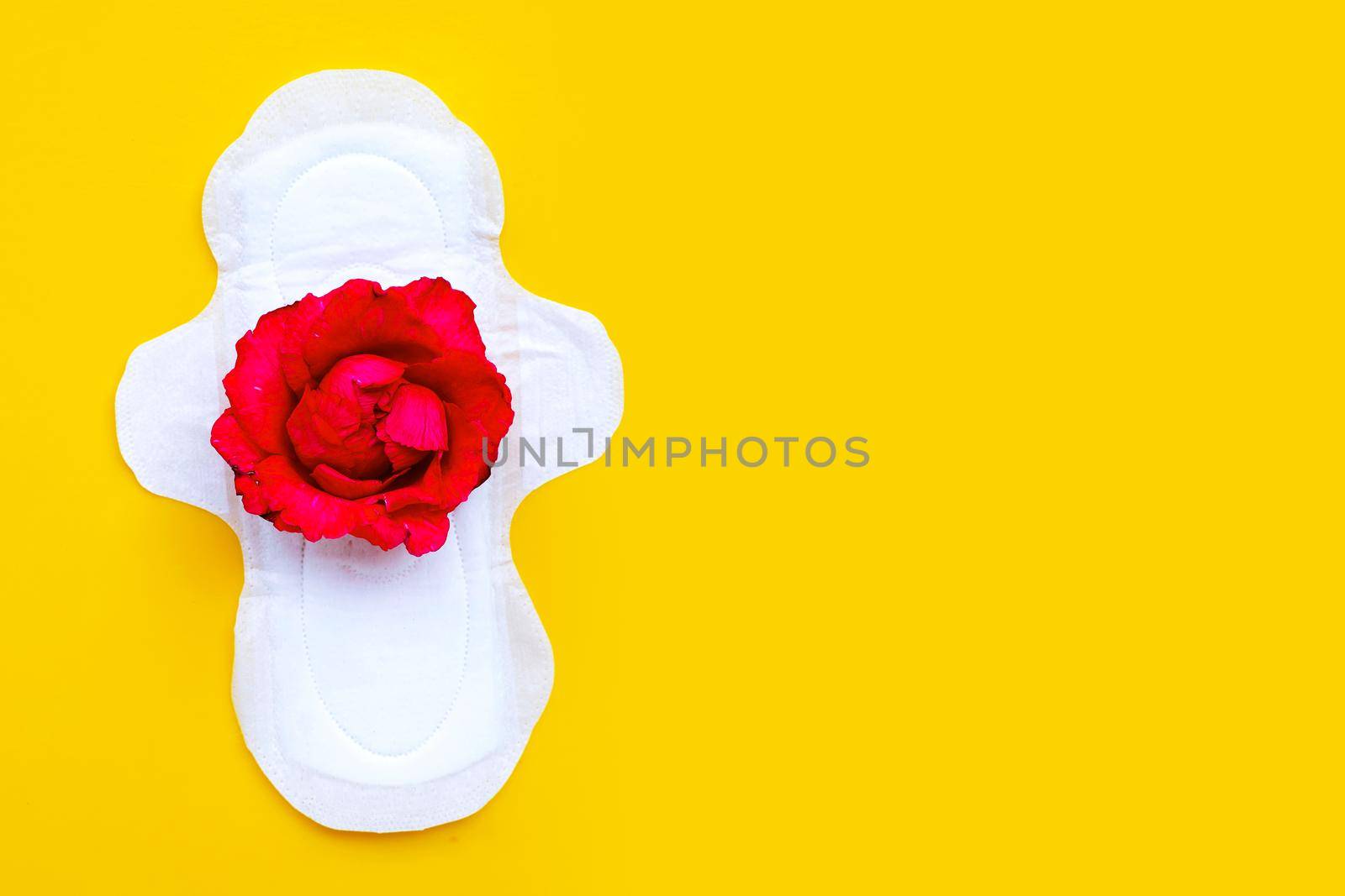 White sanitary napkin with red rose on yellow background. 