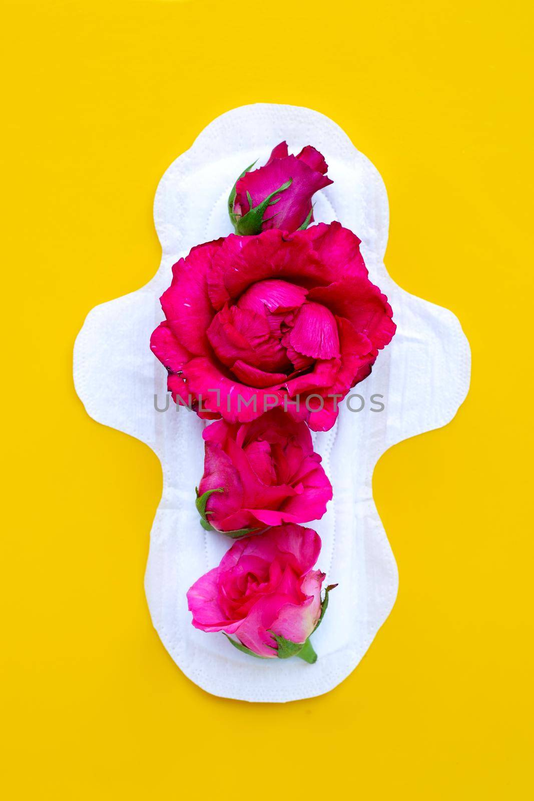 White sanitary napkin with red roses on yellow background. 