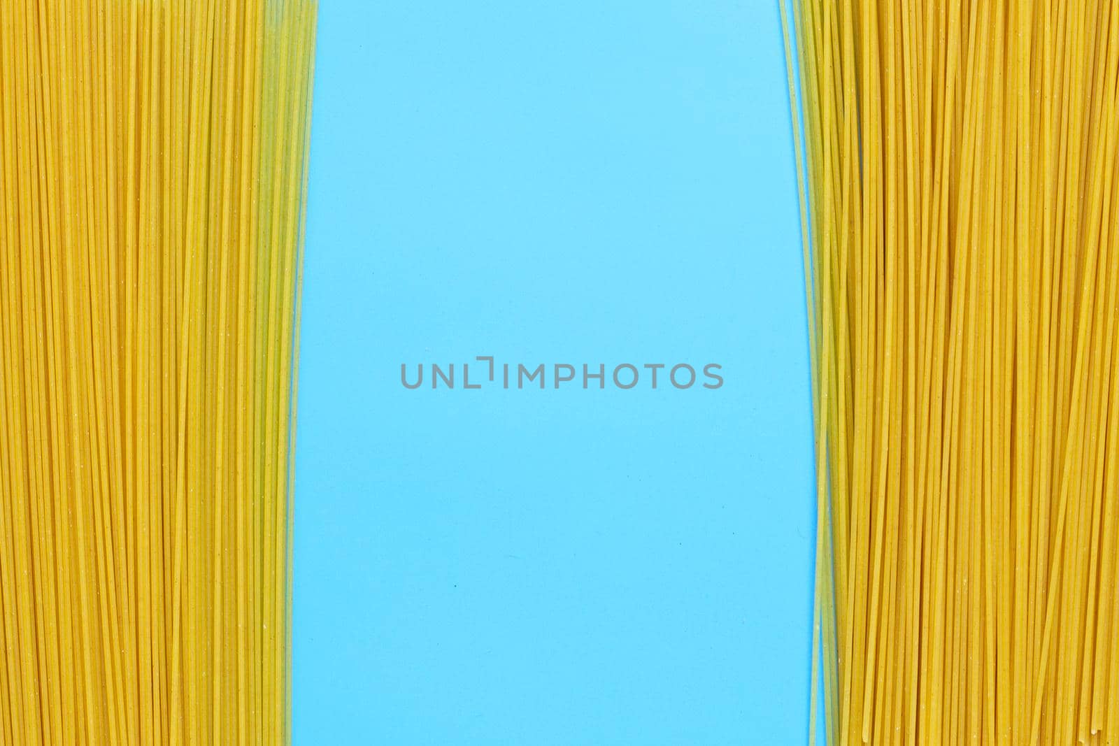 Yellow long spaghetti on blue background. Copy space