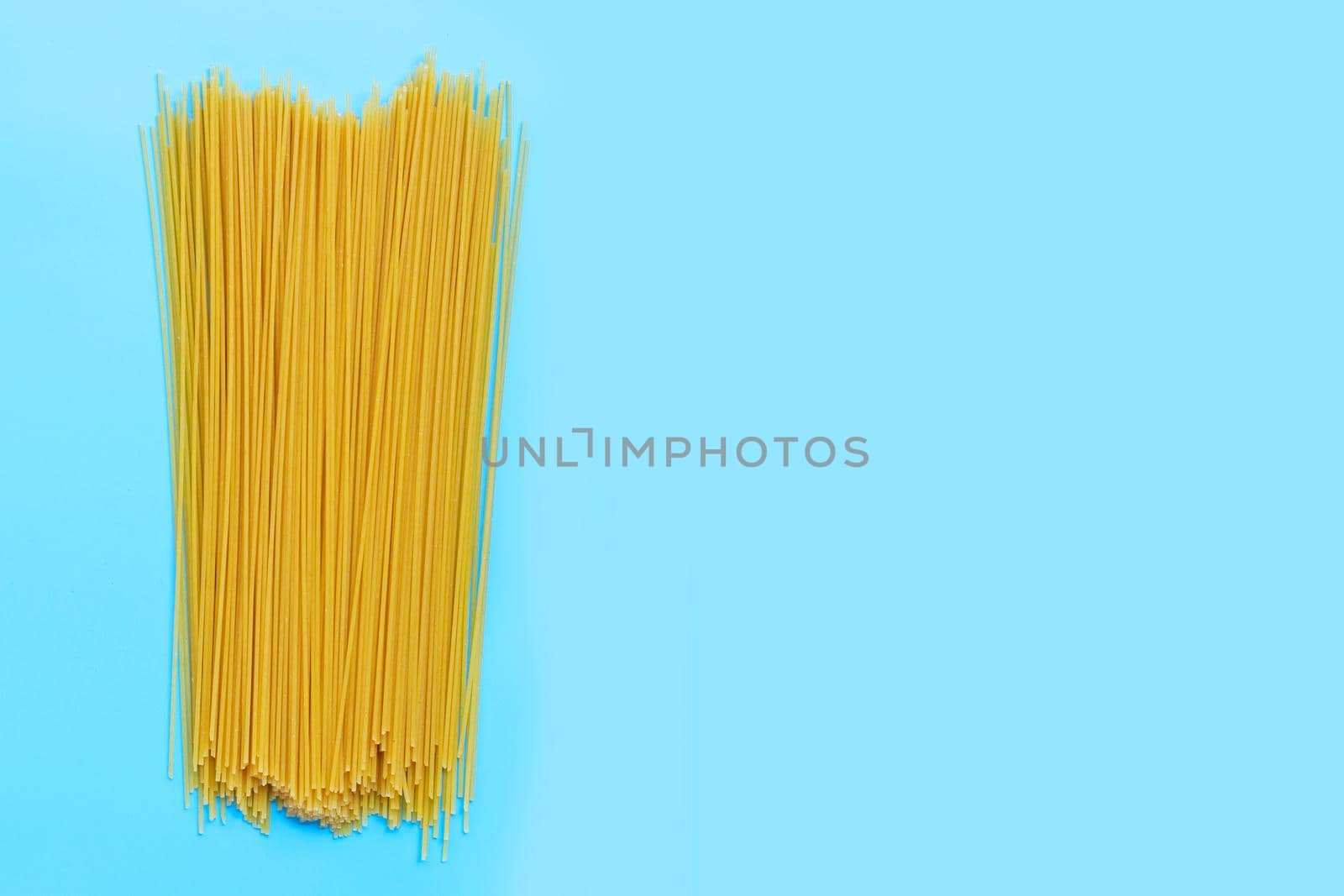 Yellow long spaghetti on blue background. Copy space