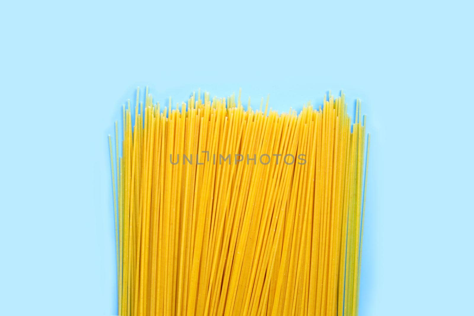 Yellow long spaghetti on blue background. Copy space