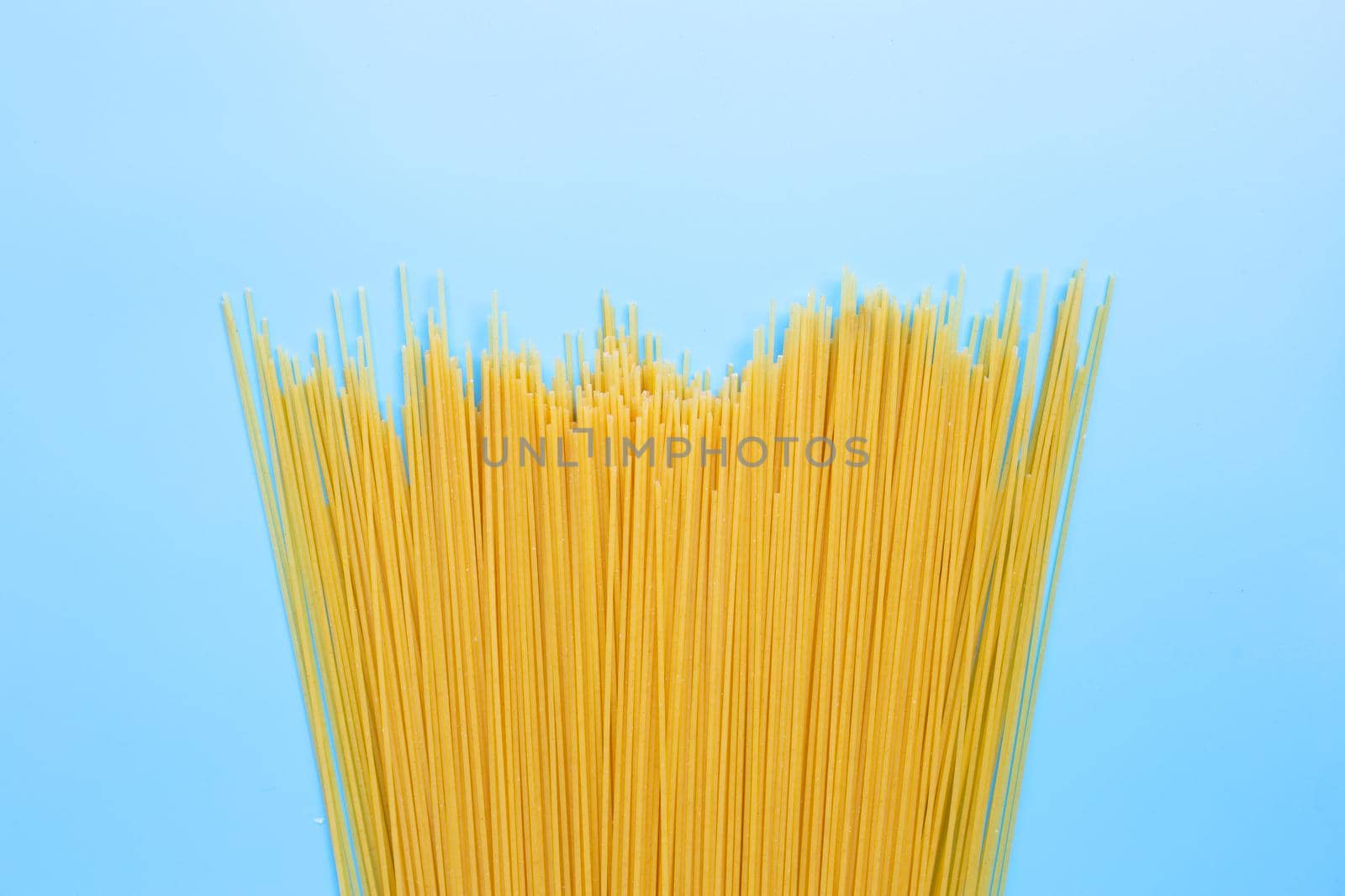 Yellow long spaghetti on blue background. Copy space