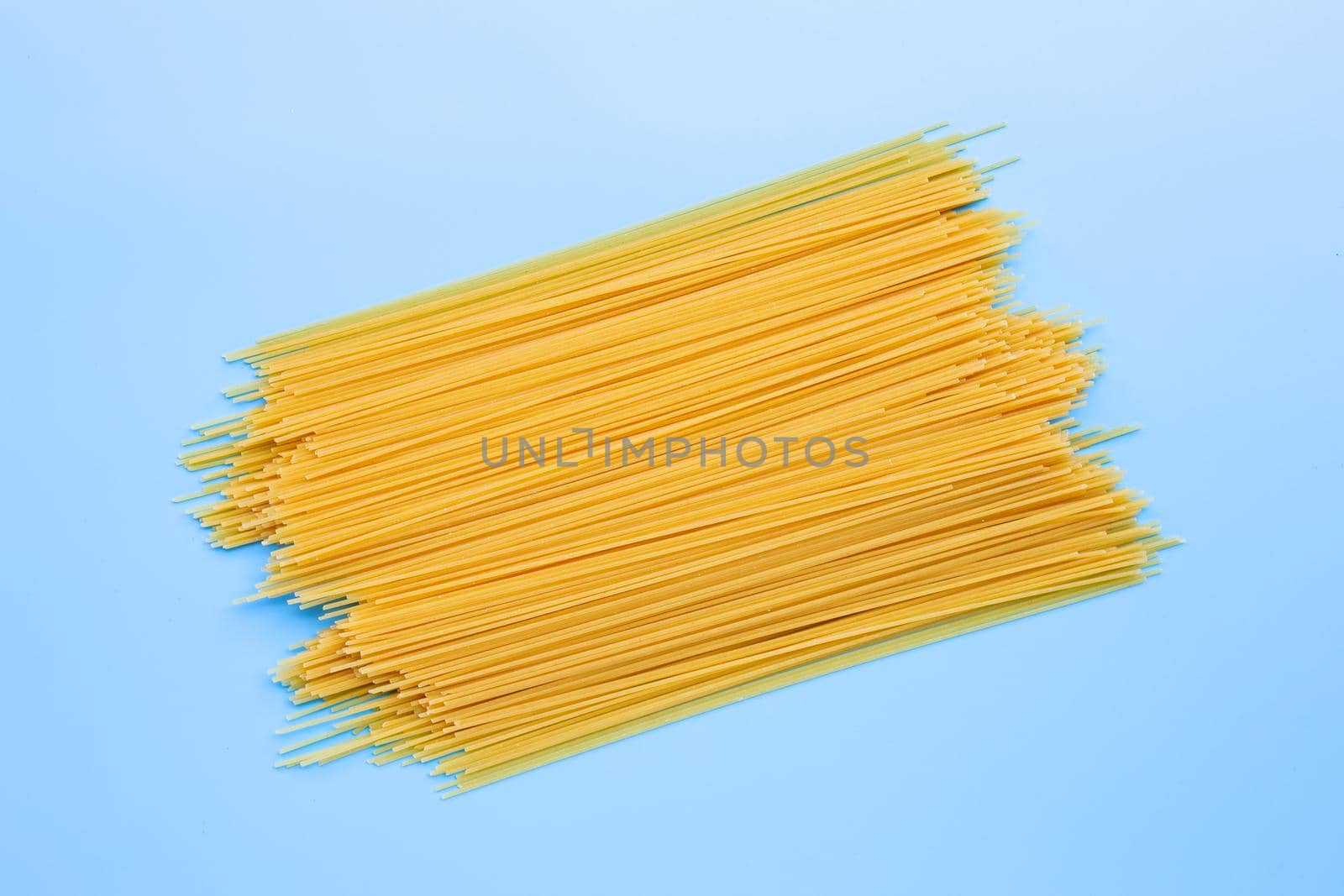 Yellow long spaghetti on blue background. Copy space