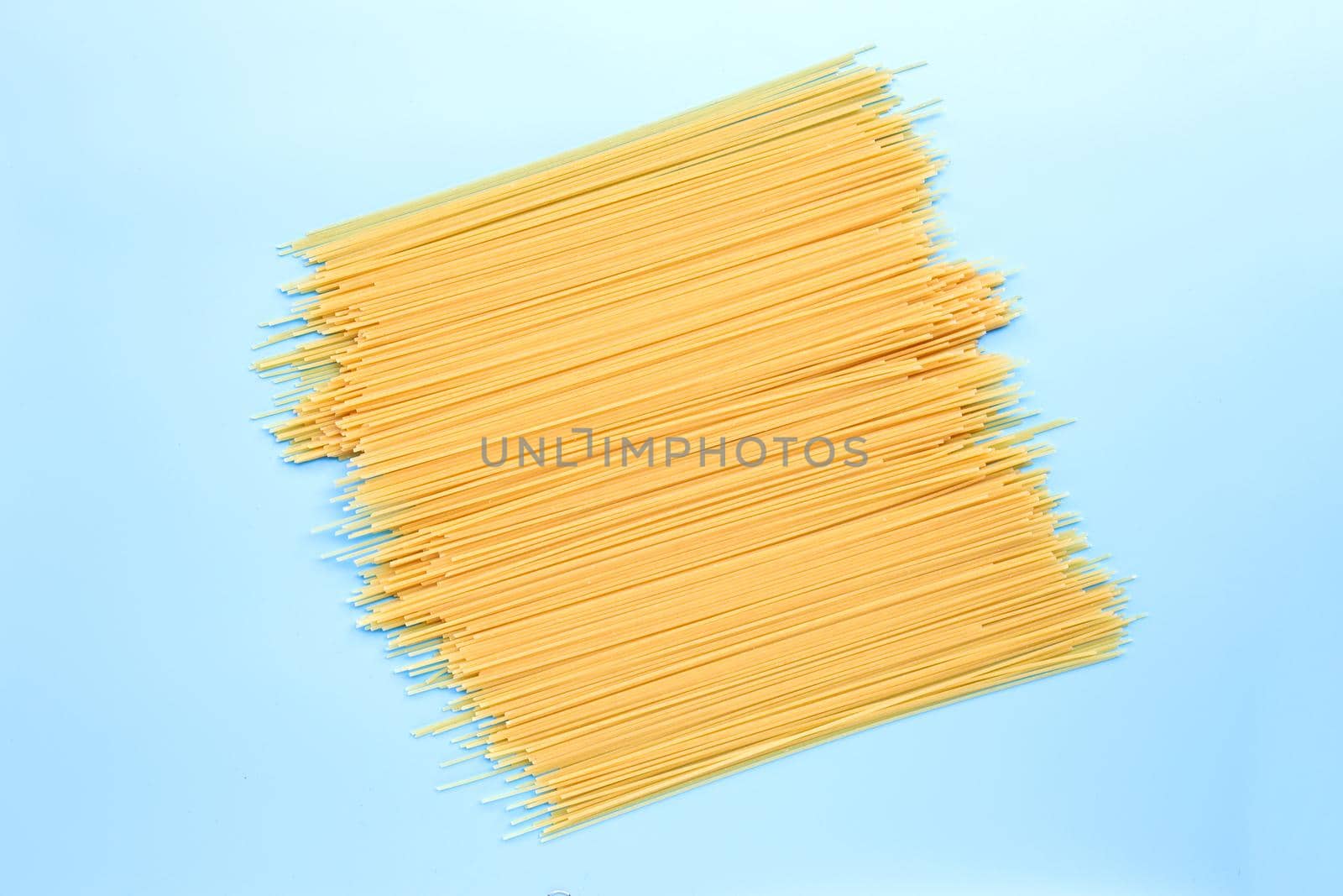 Yellow long spaghetti on blue background. Copy space