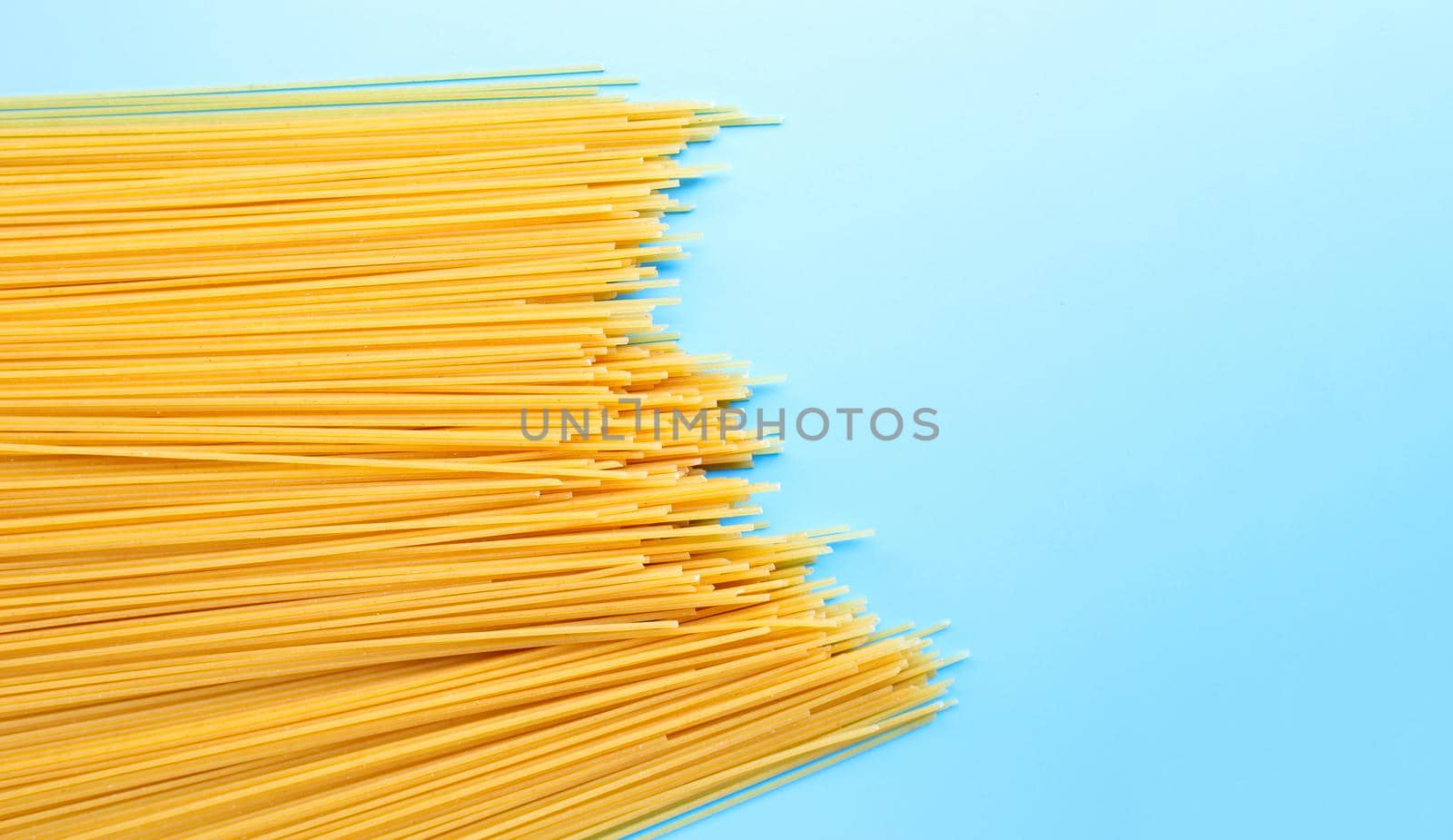 Yellow long spaghetti on blue background. Copy space