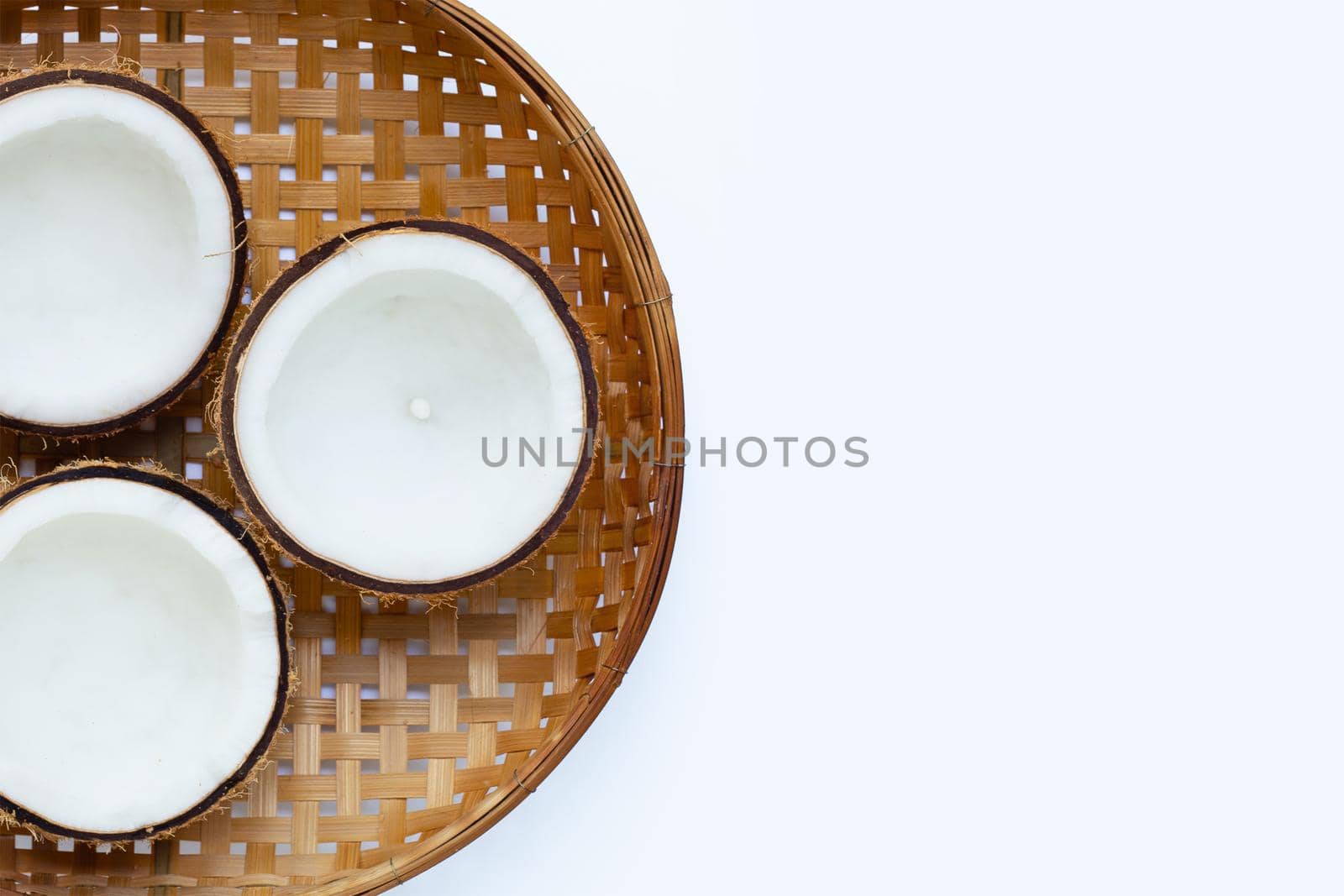Half coconuts on wooden bamboo threshing basket on white background. Copy space
