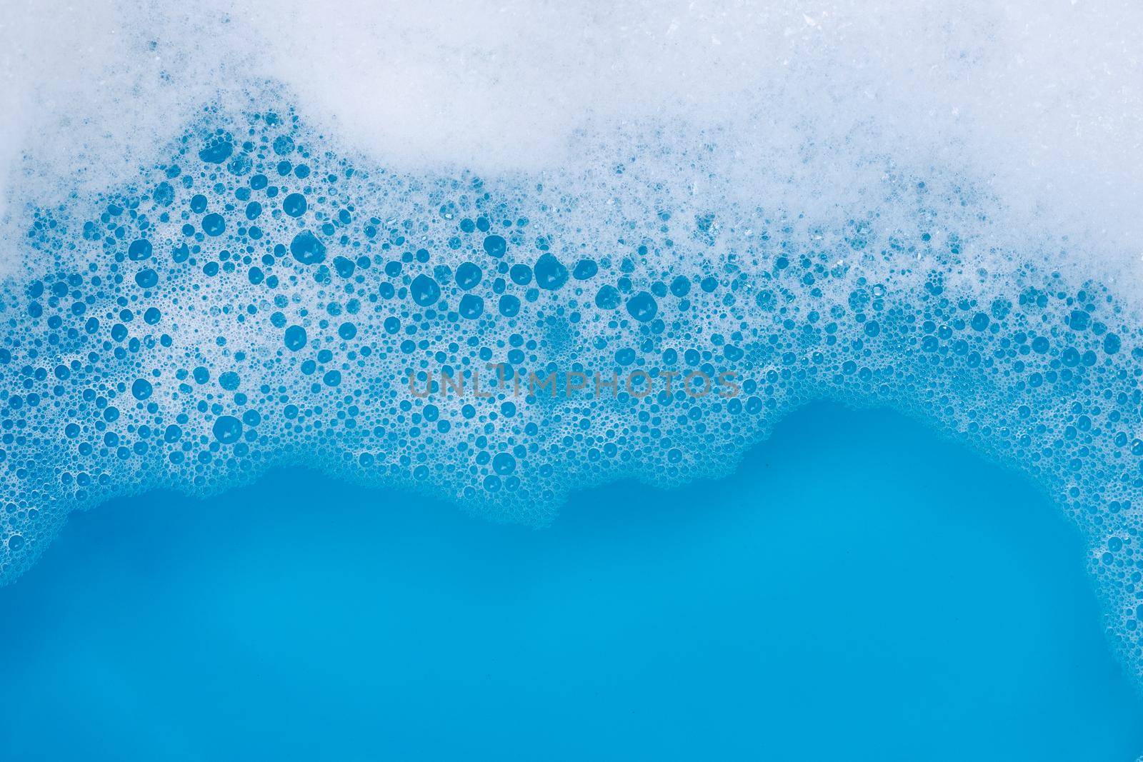 Detergent foam bubble on blue background. Top view