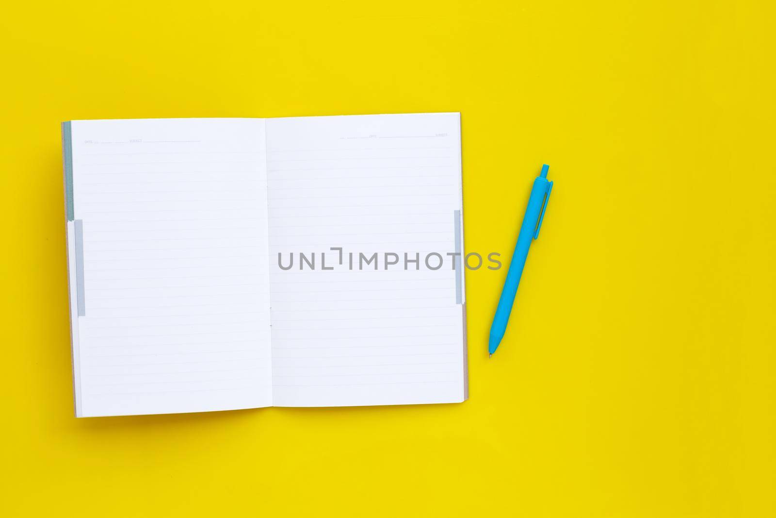 Notebook with pen on yellow background.