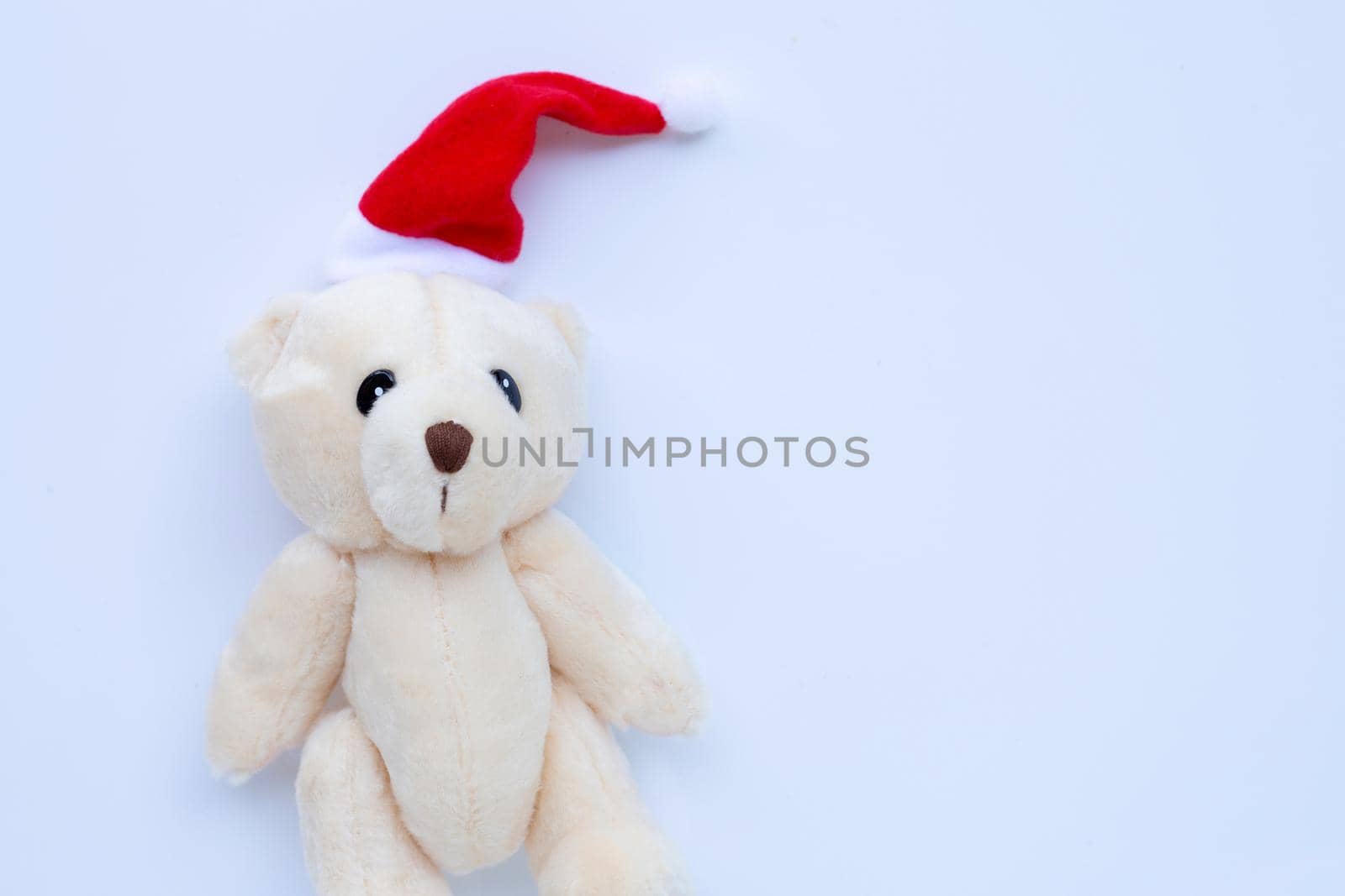 Toy bear wearing a santa hat on white background. Christmas holidays concept