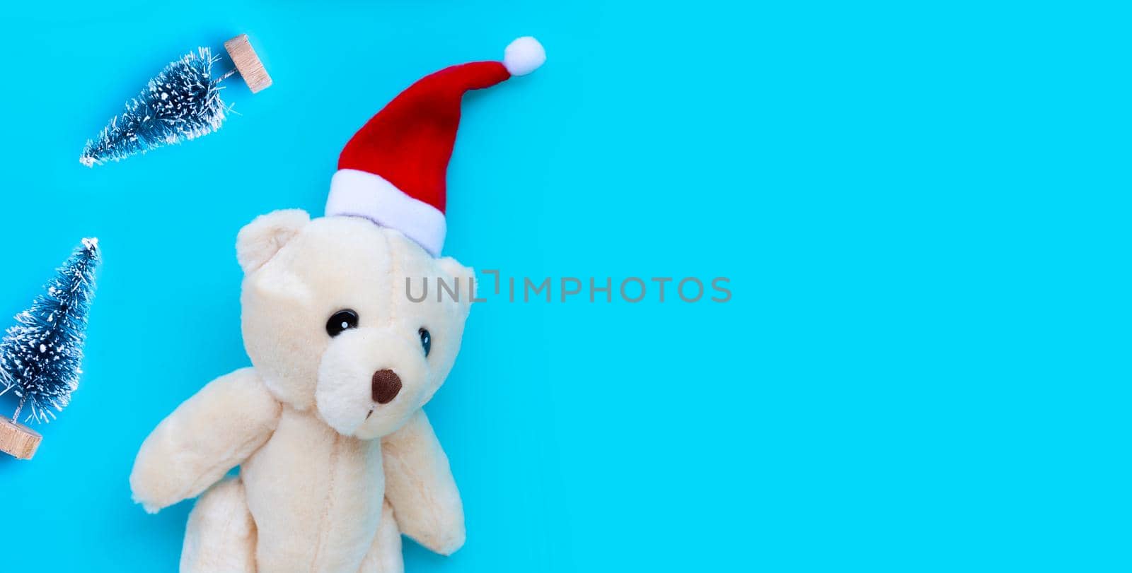 Toy bear wearing a santa hat on blue background. Christmas holidays concept