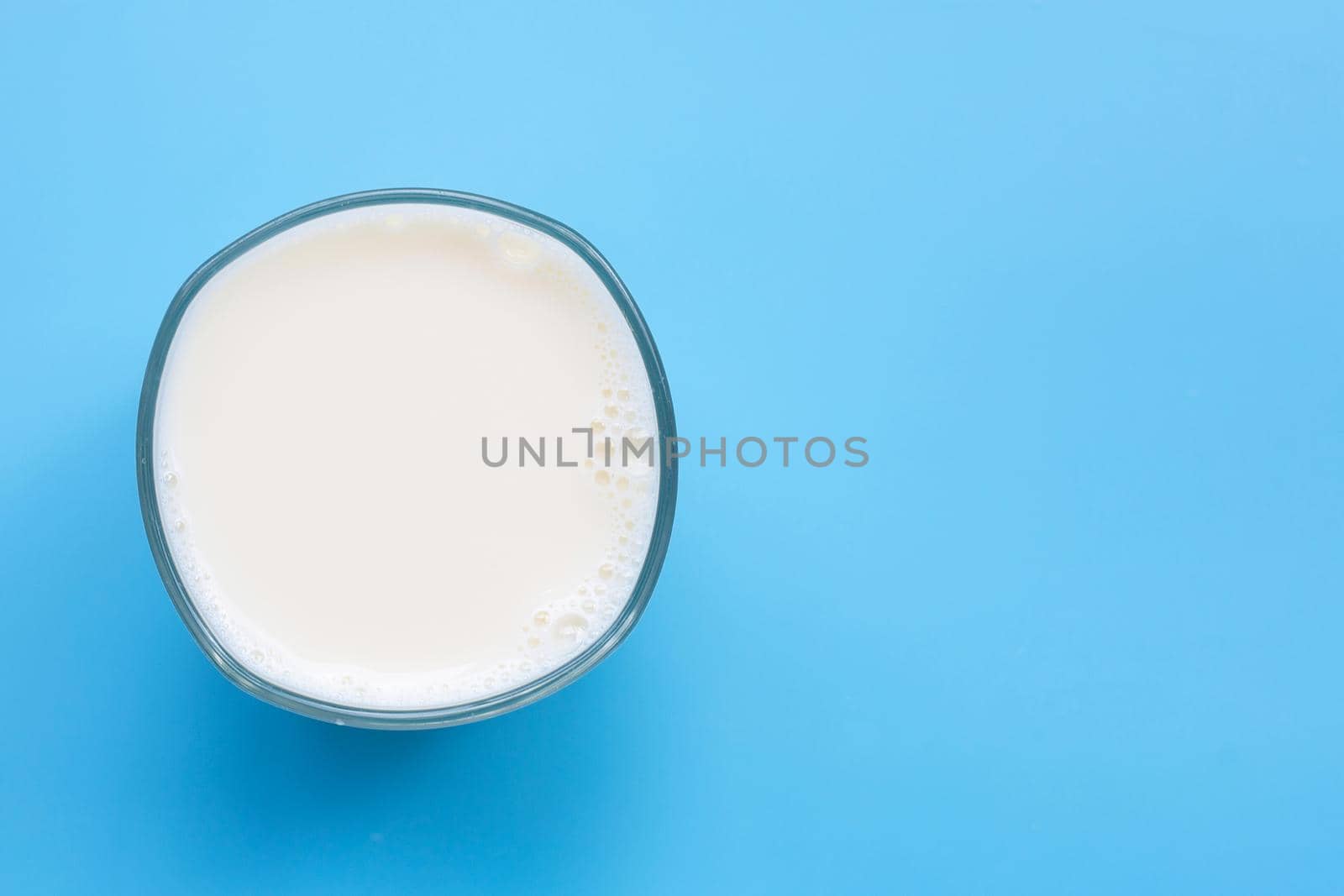 Glass of milk on blue background. Copy space