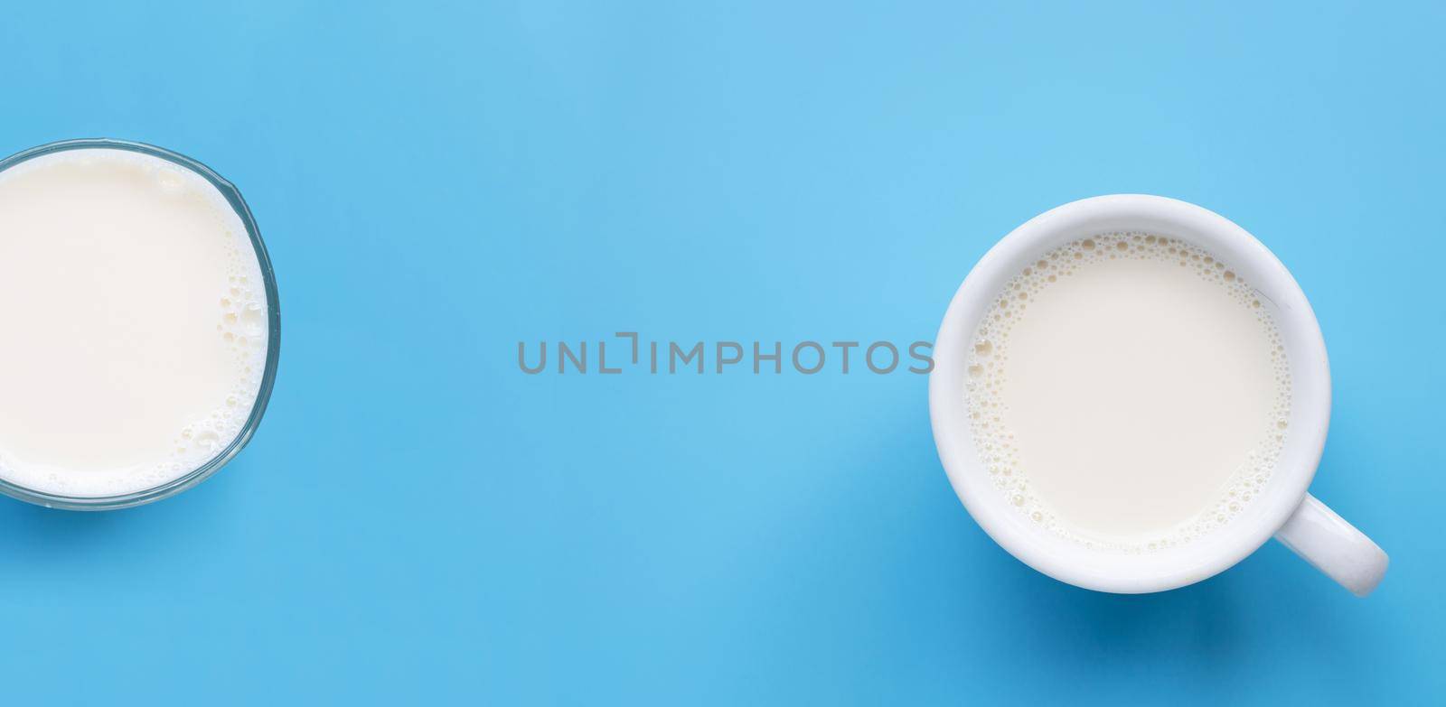 Glass with cup of milk on blue background. Copy space