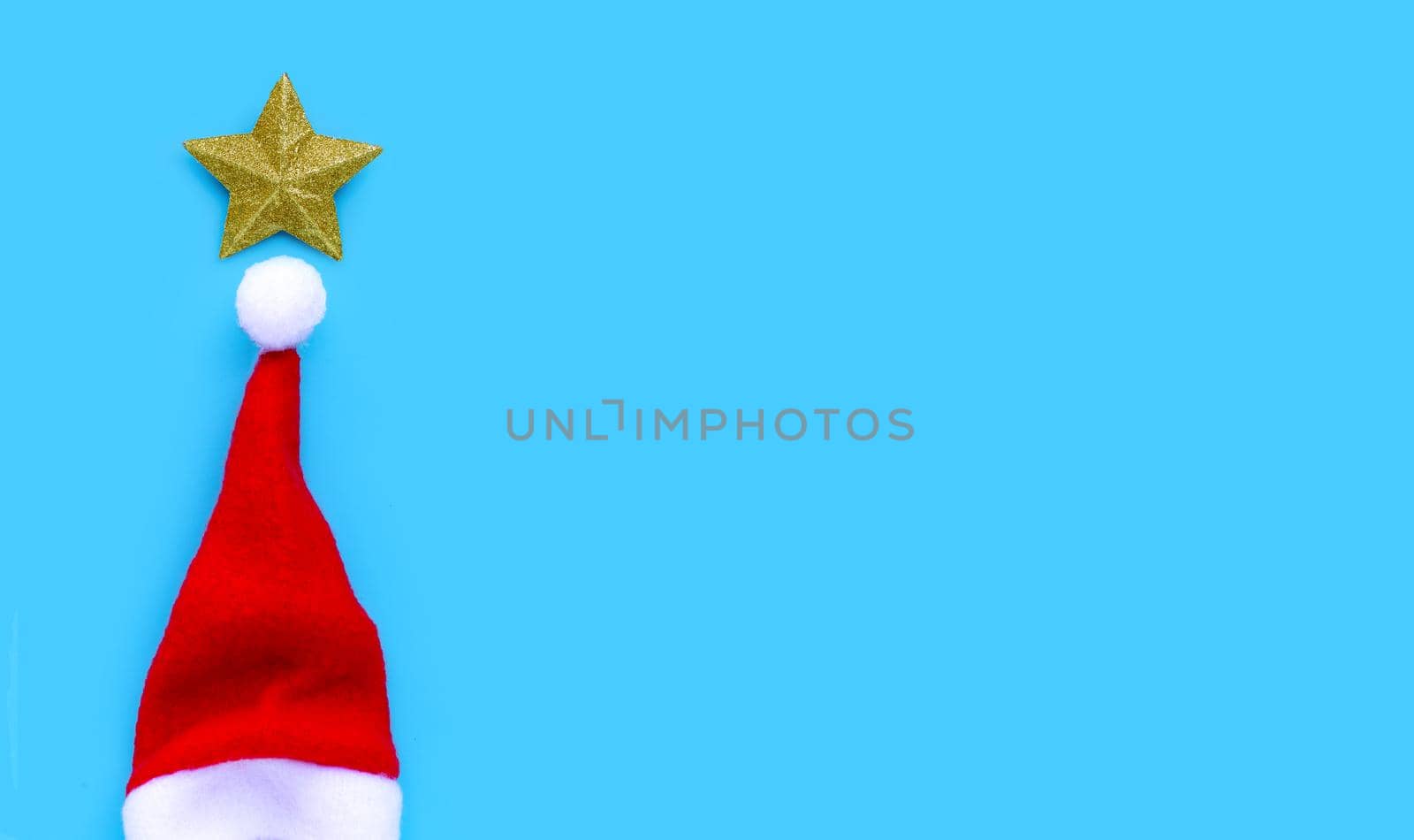 Golden star with santa hat on blue background. Copy space
