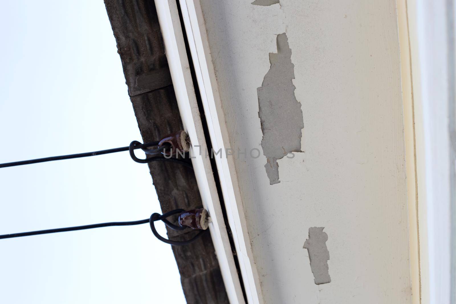 White color paint peeling off on ceiling house. Under the roof