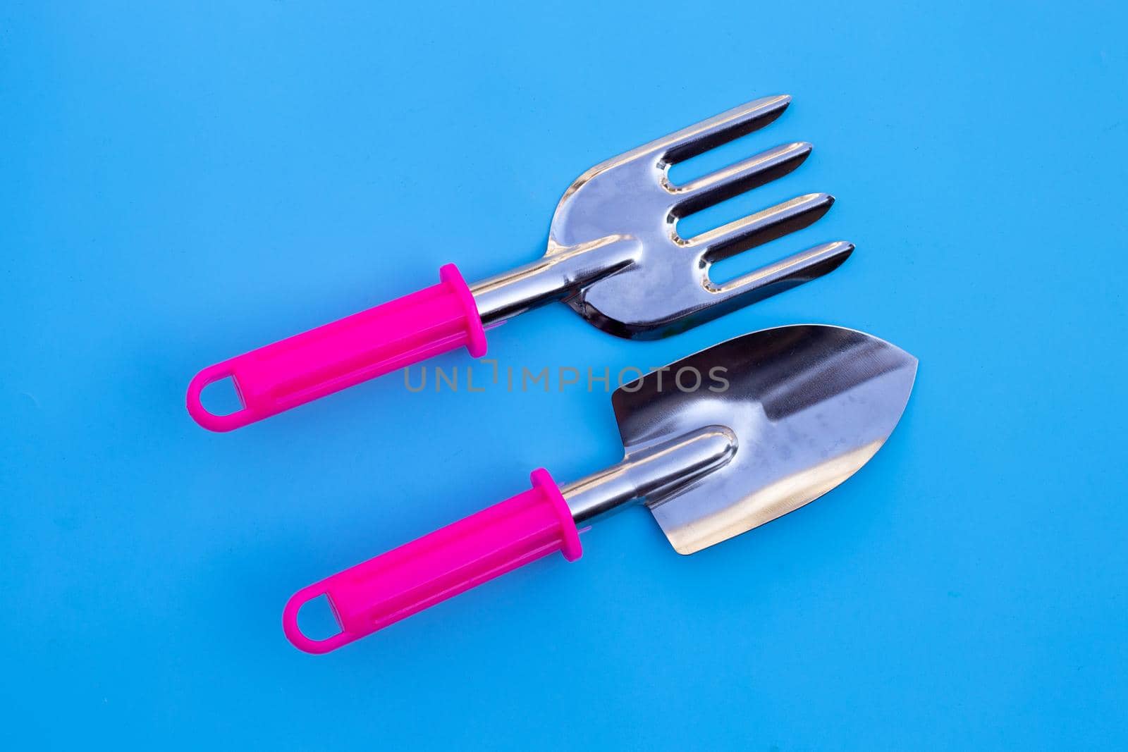 Garden shovel and fork isolated on blue background.