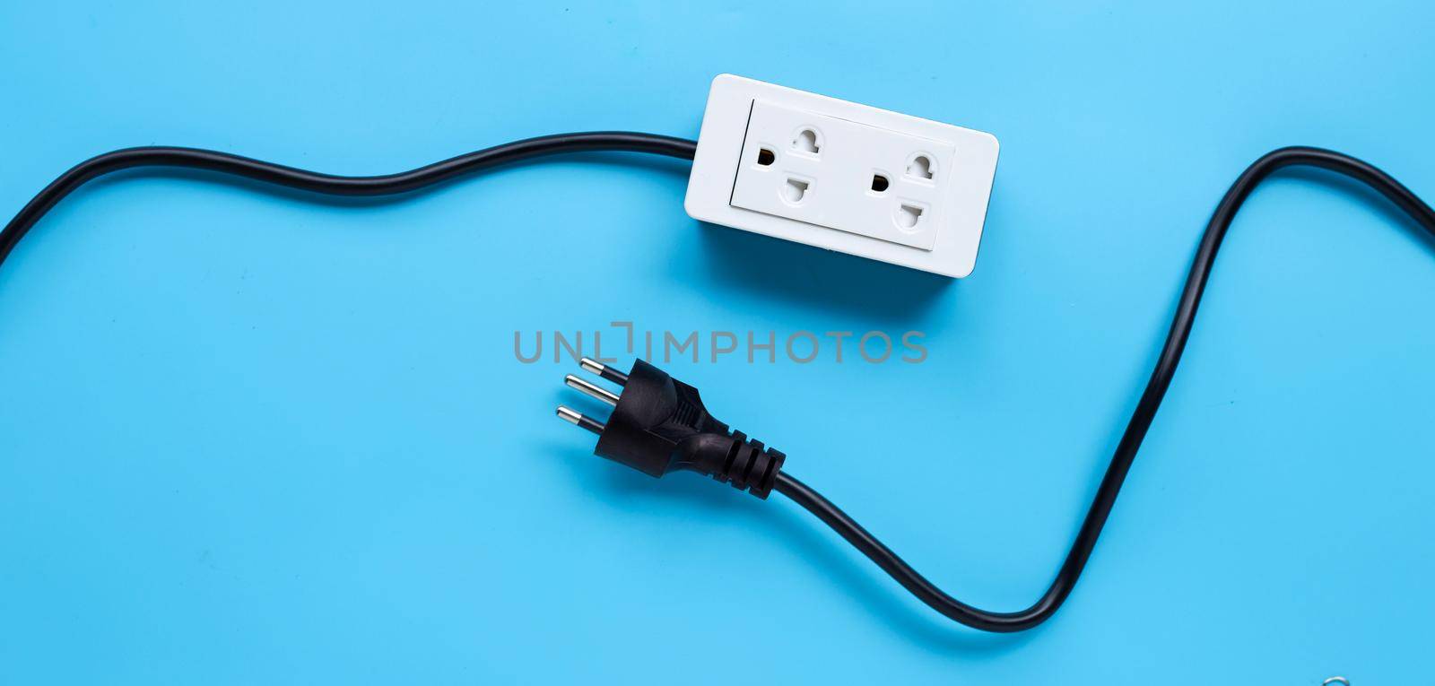Electrical power strip and plug on blue background. Top view by Bowonpat