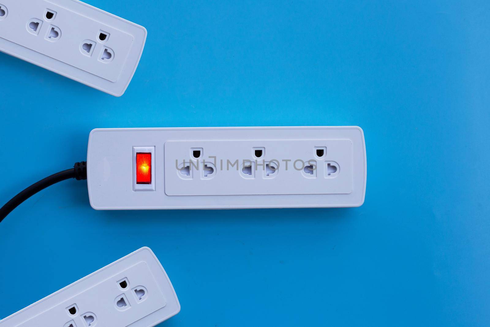 Electrical power strip on blue background. Top view