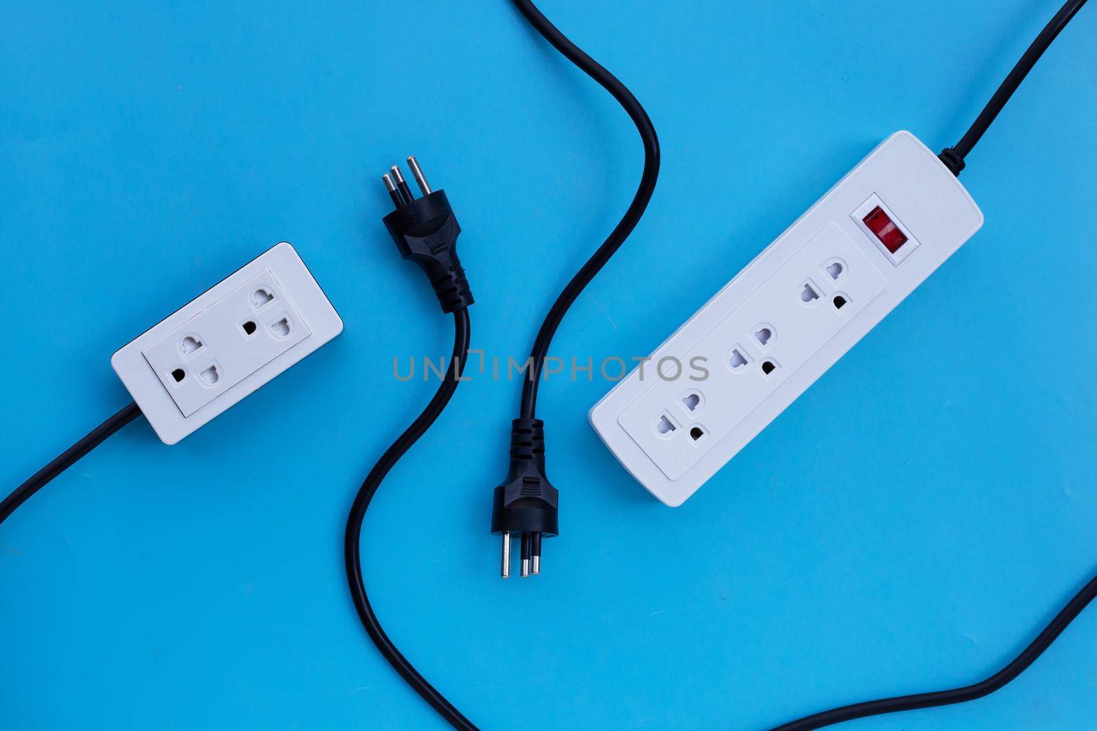 Electrical power strip and plug on blue background. Top view