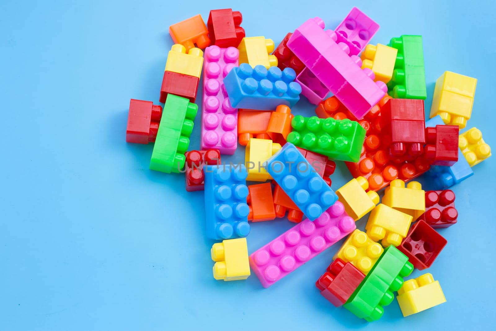 Plastic building blocks on blue background.