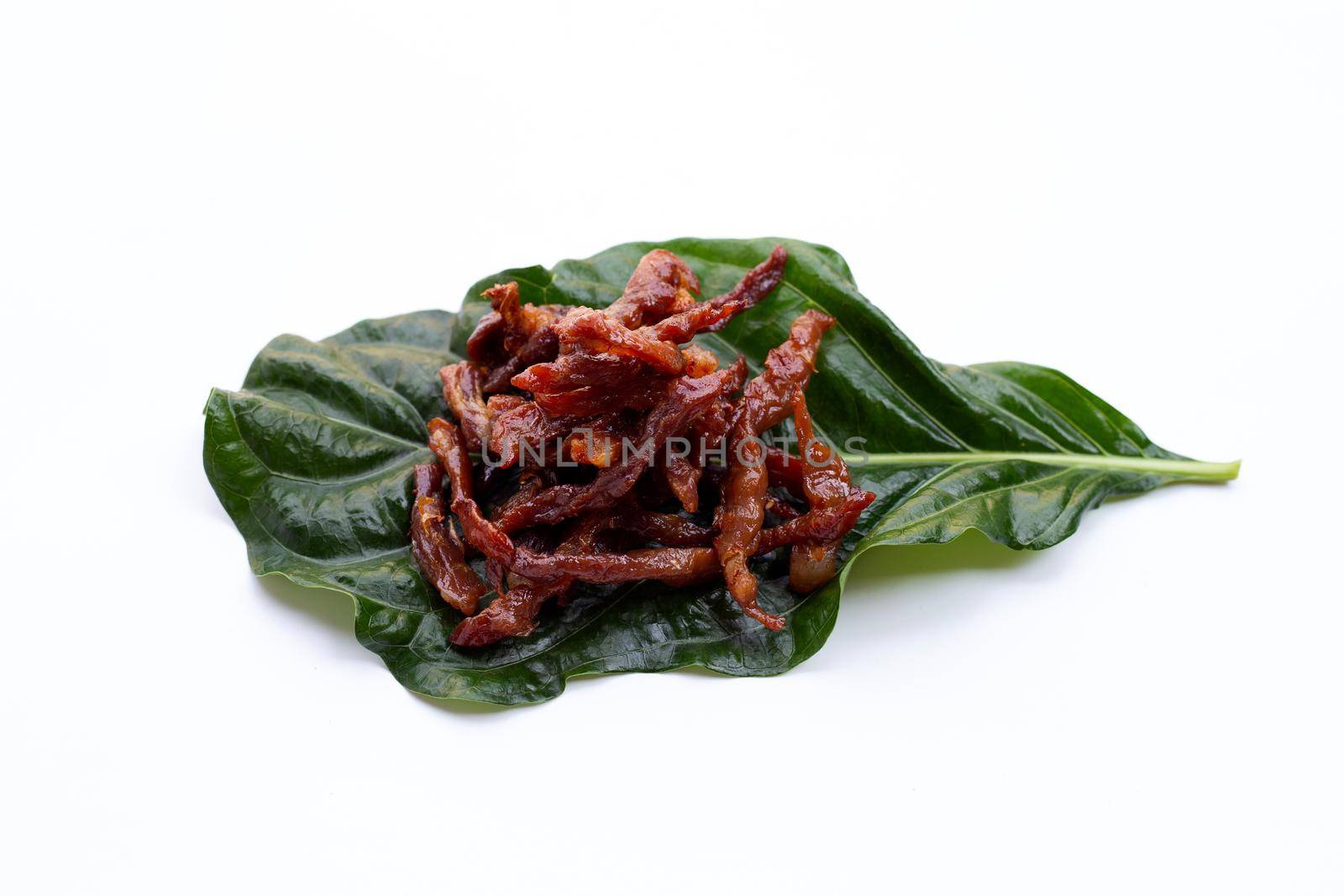 Deep fried sun-dried pork on noni or morinda citrifolia leaf on white background.