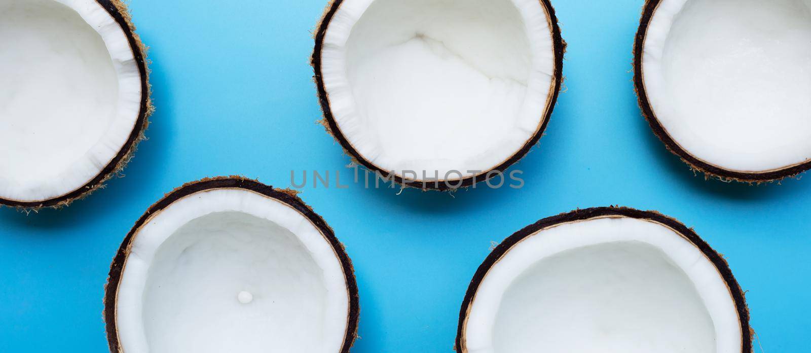 Half coconut on a blue background. Copy space