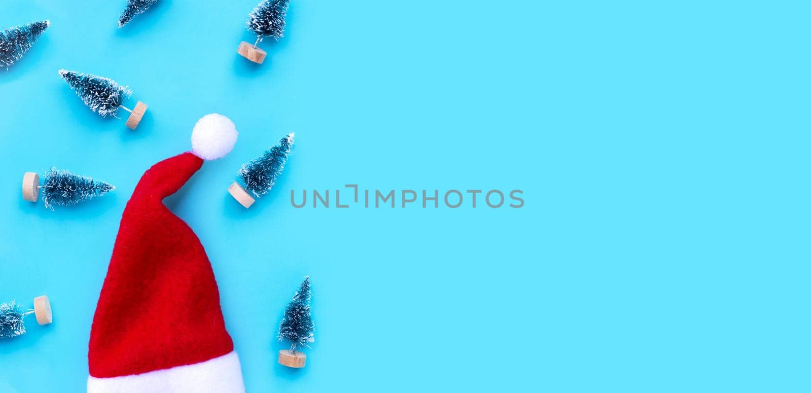 Santa hat with miniature christmas pine tree on blue background.