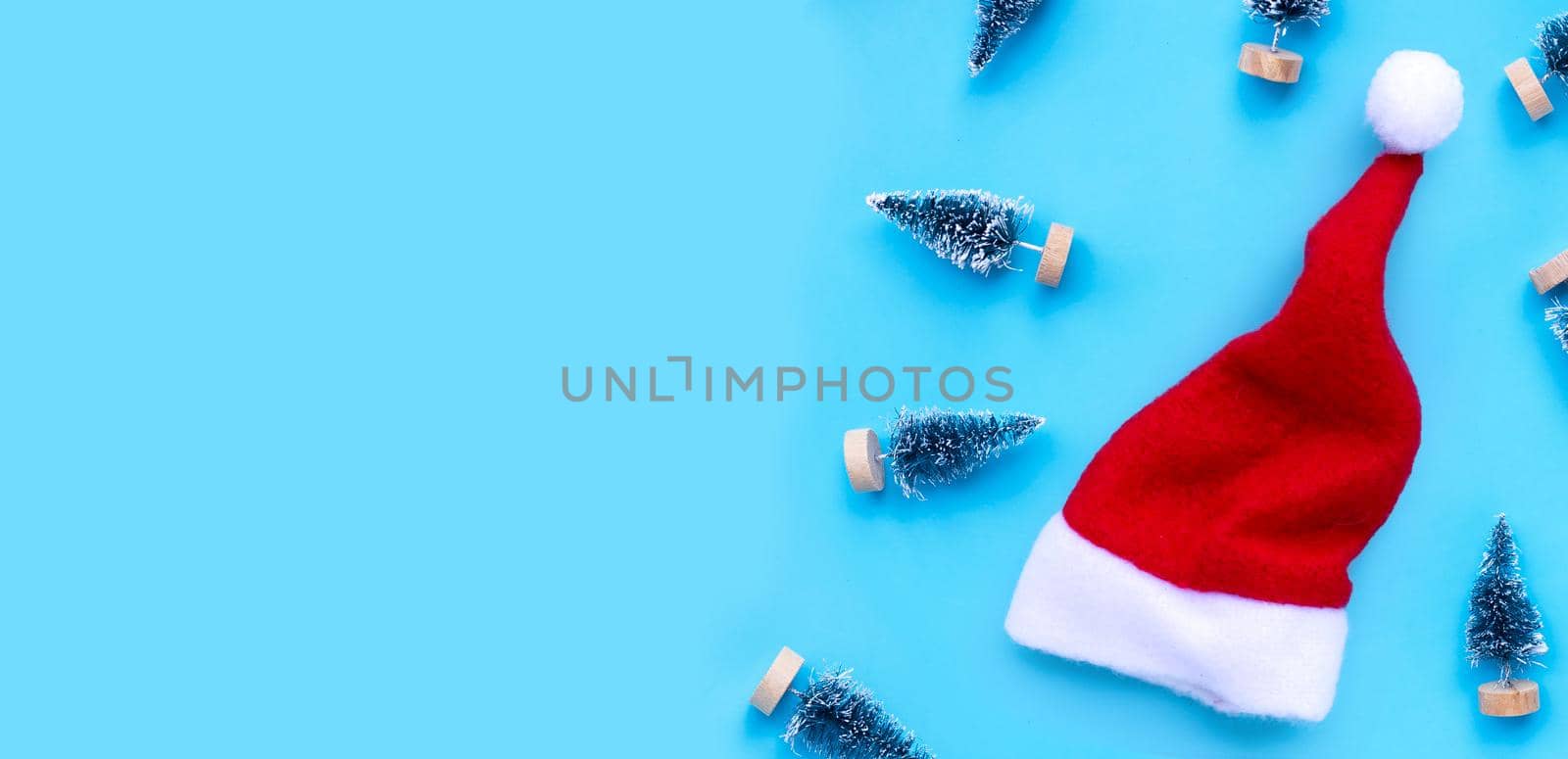 Santa hat with miniature christmas pine tree on blue background.