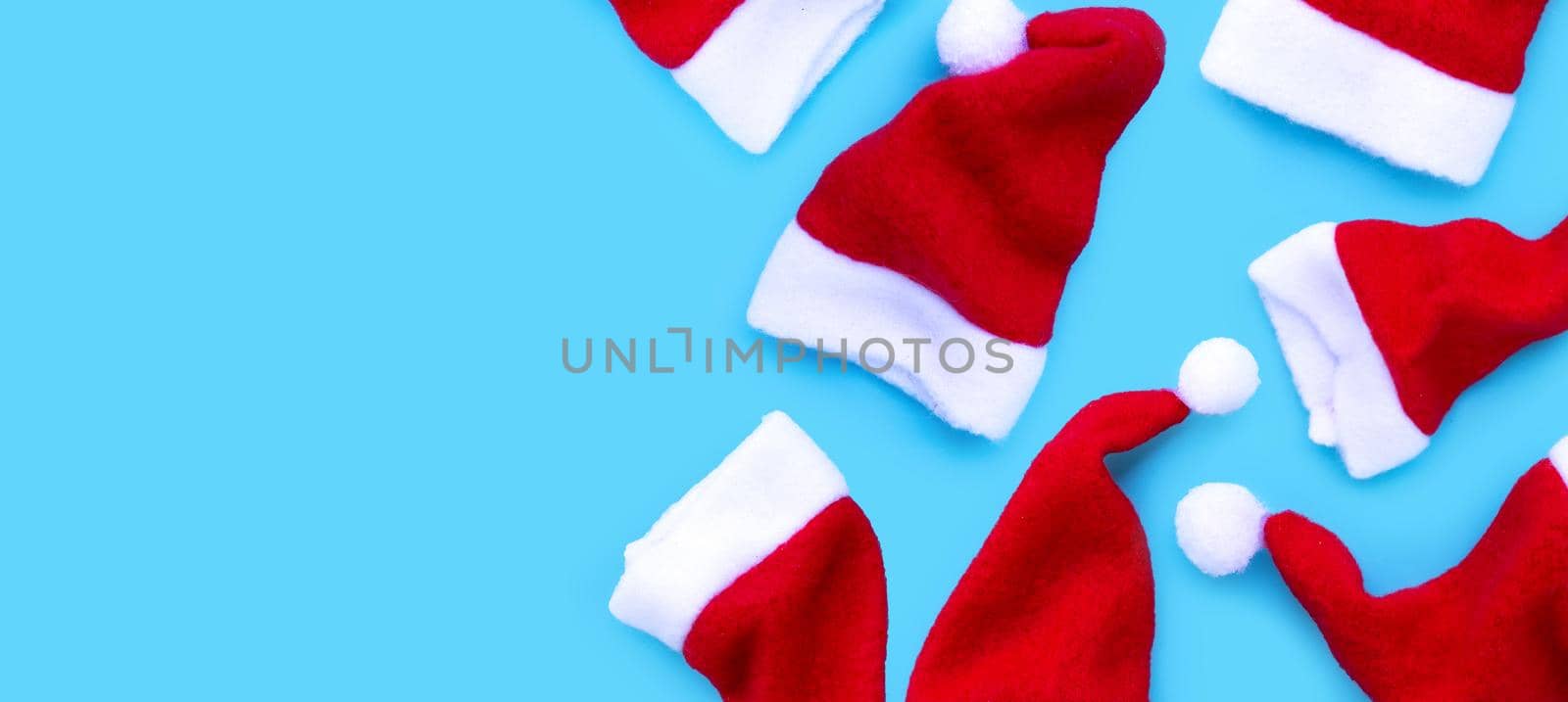 Merry Christmas and Happy Holidays. Santa hats on blue background. 