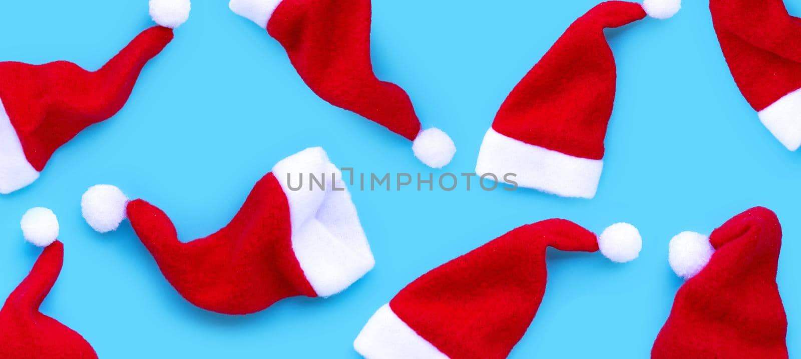 Merry Christmas and Happy Holidays. Santa hats on blue background. 