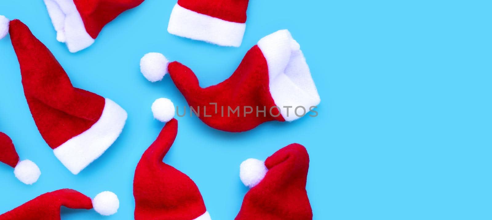 Merry Christmas and Happy Holidays. Santa hats on blue background. 