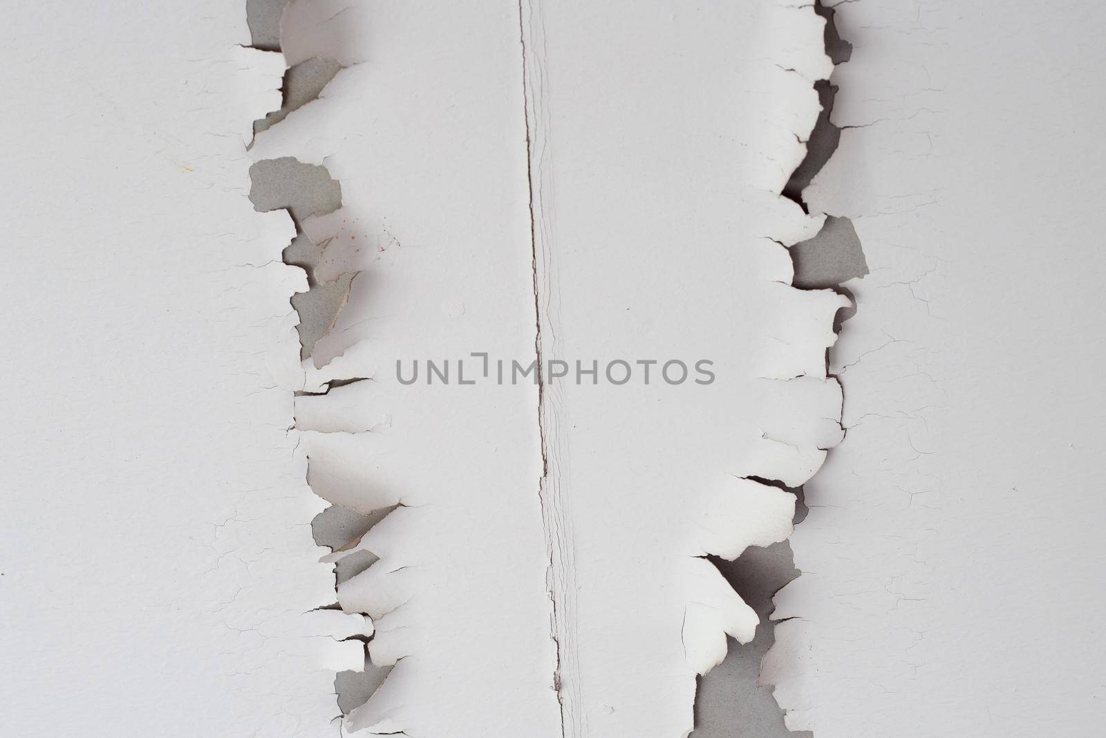 White color paint peeling off on ceiling house. Under the roof