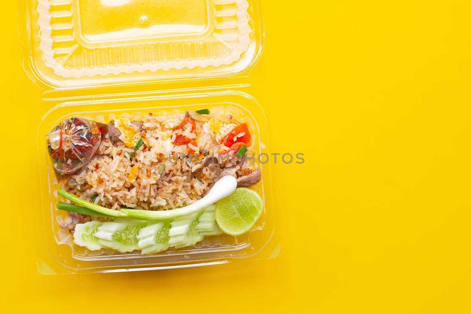 Fried rice in plastic box on yellow background.