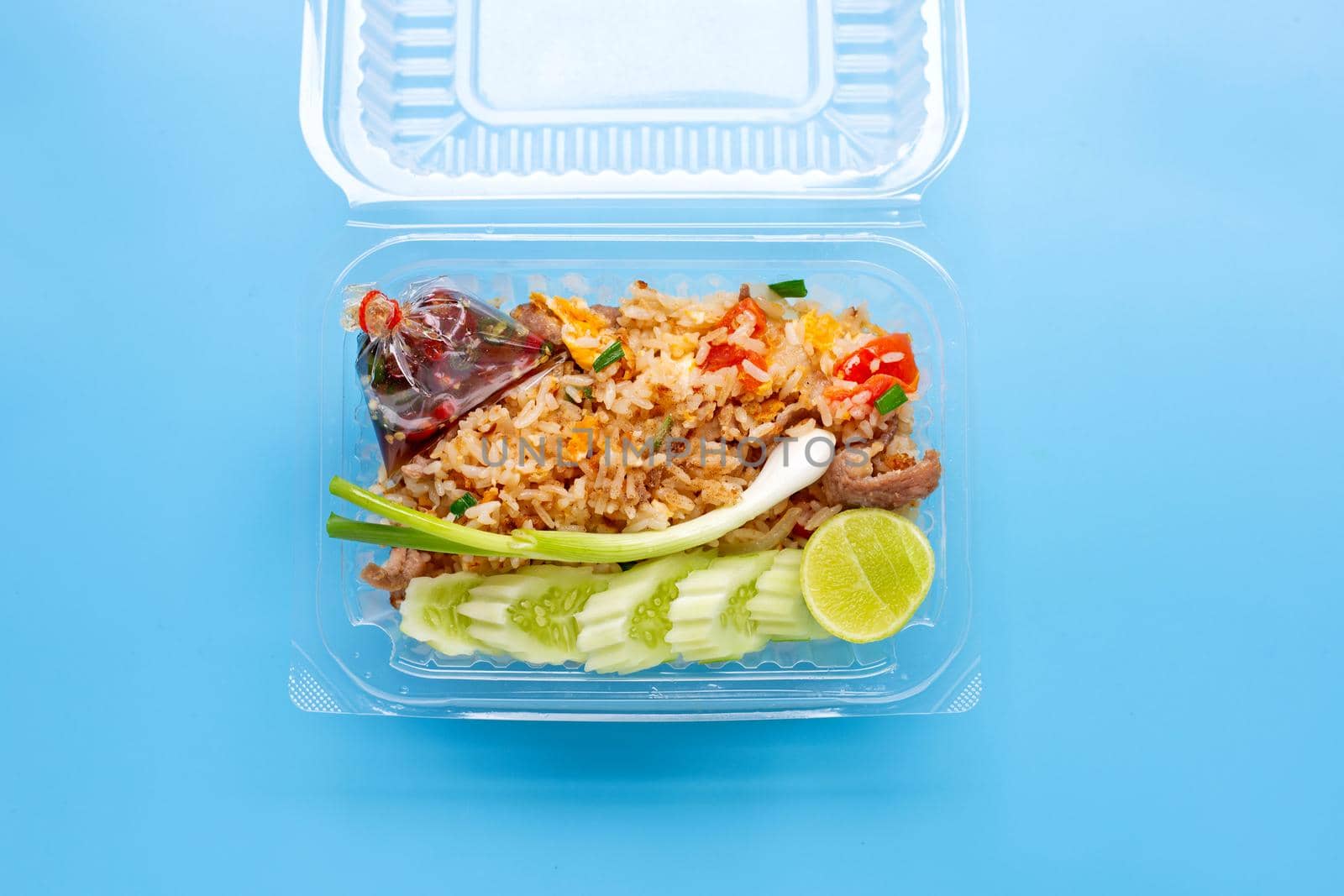 Fried rice in plastic box on blue background.
